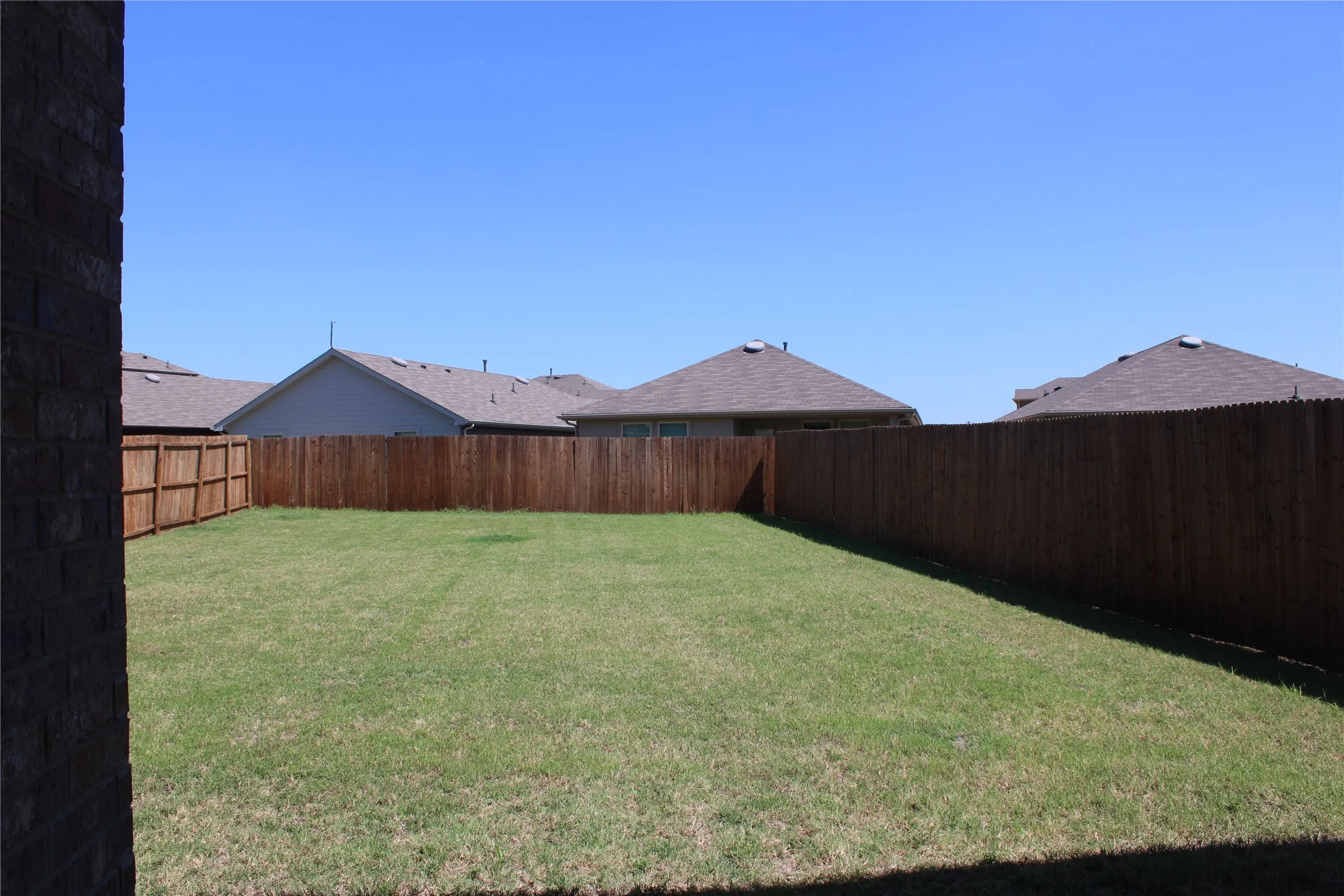 Expansive grassy backyard featuring a perimeter wood privacy fence
