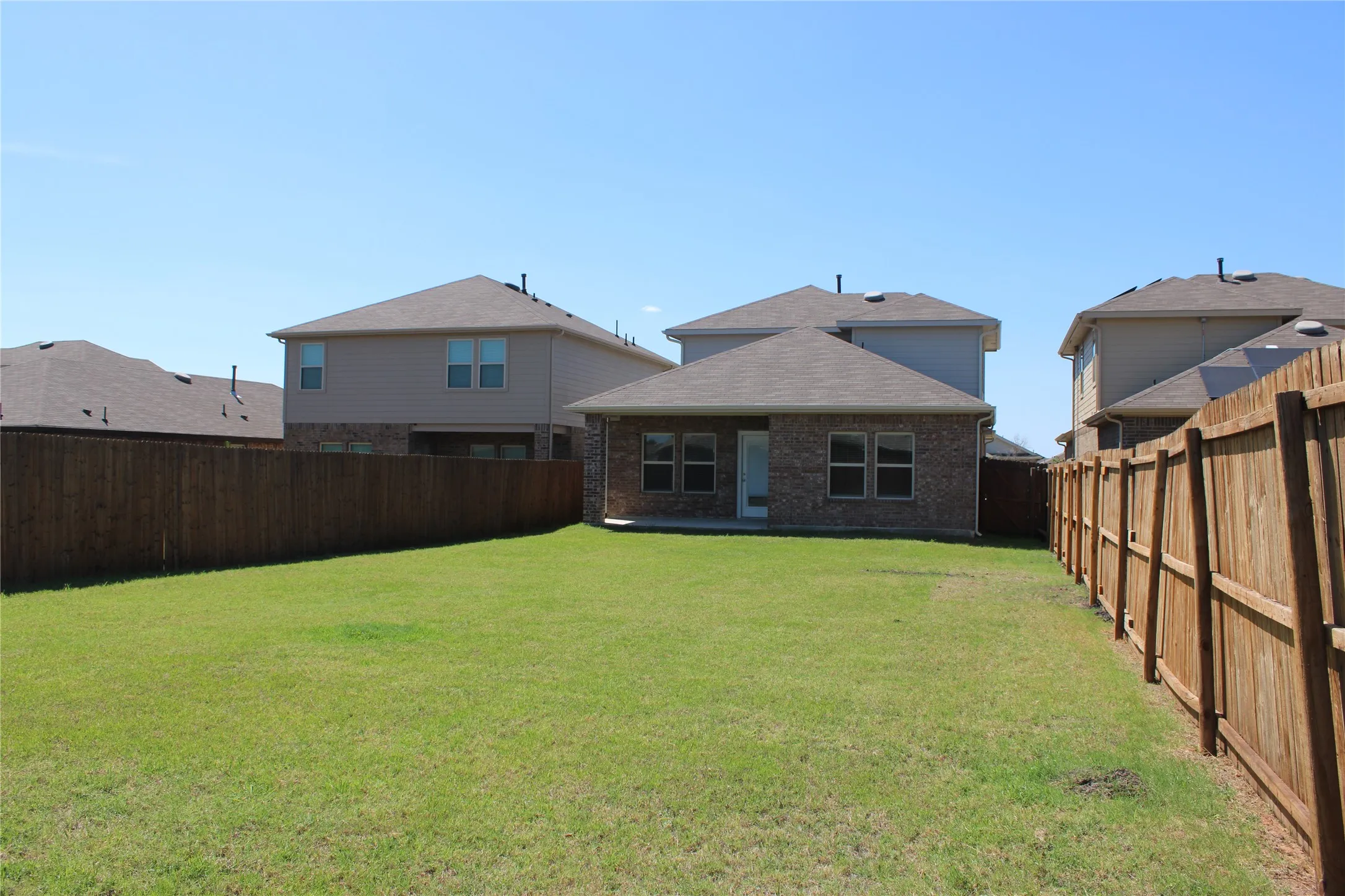Expansive fenced backyard featuring a manicured lawn