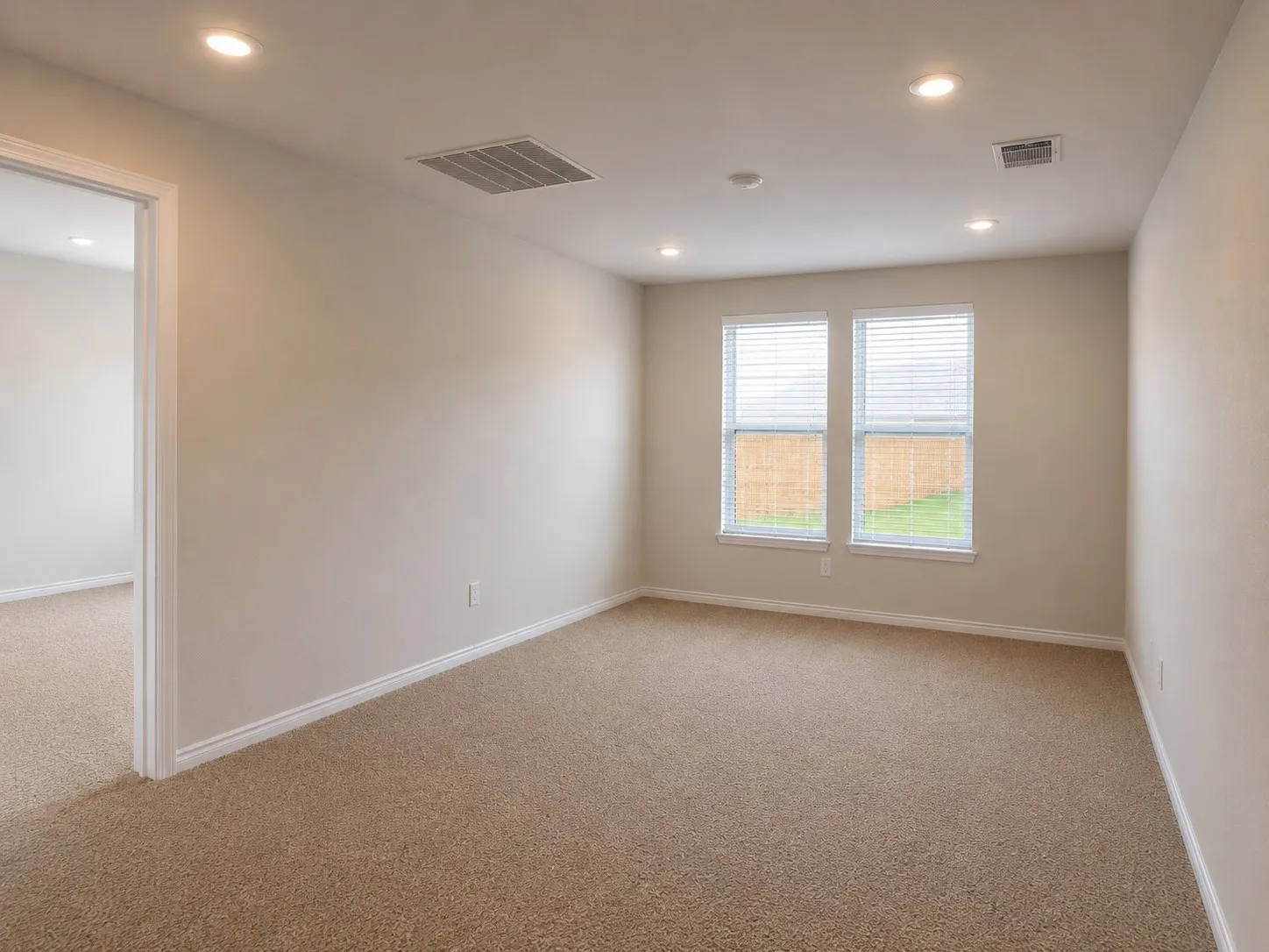 Bright room featuring light-toned carpeting, neutral wall paint, and white trim