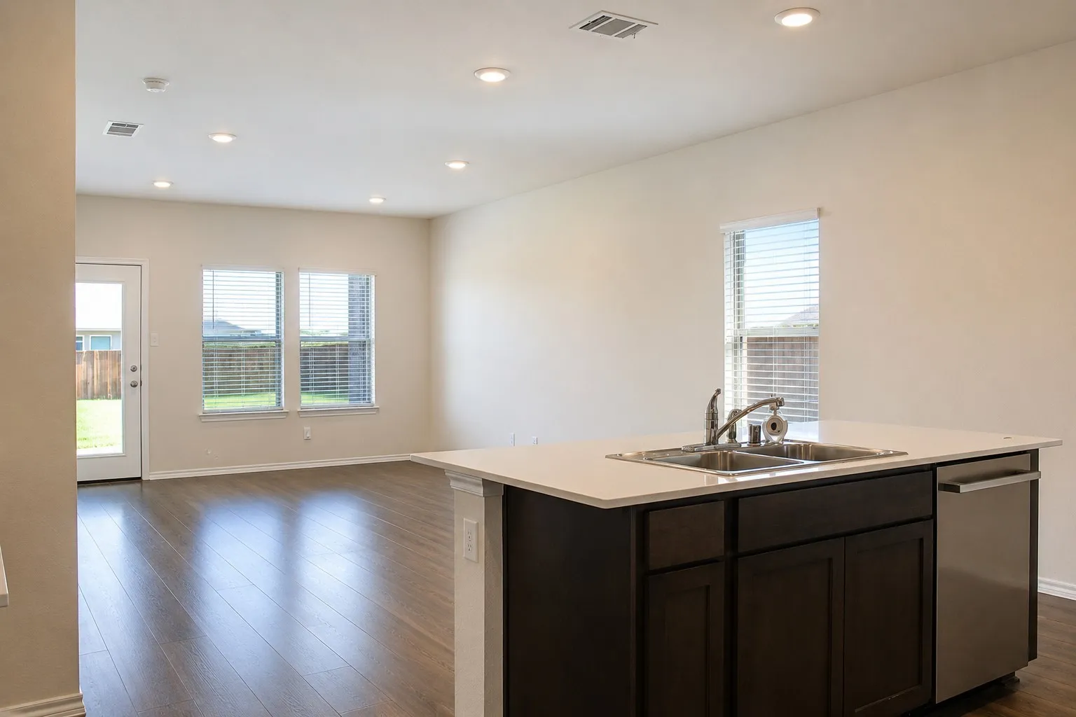 Kitchen island featuring a stainless steel double basin sink, chrome faucet, and integrated dishwasher