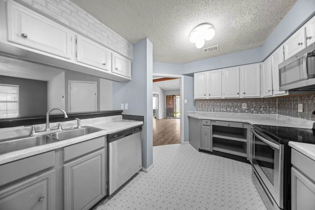 Kitchen featuring white upper cabinetry, gray lower cabinetry, and a patterned tile backsplash