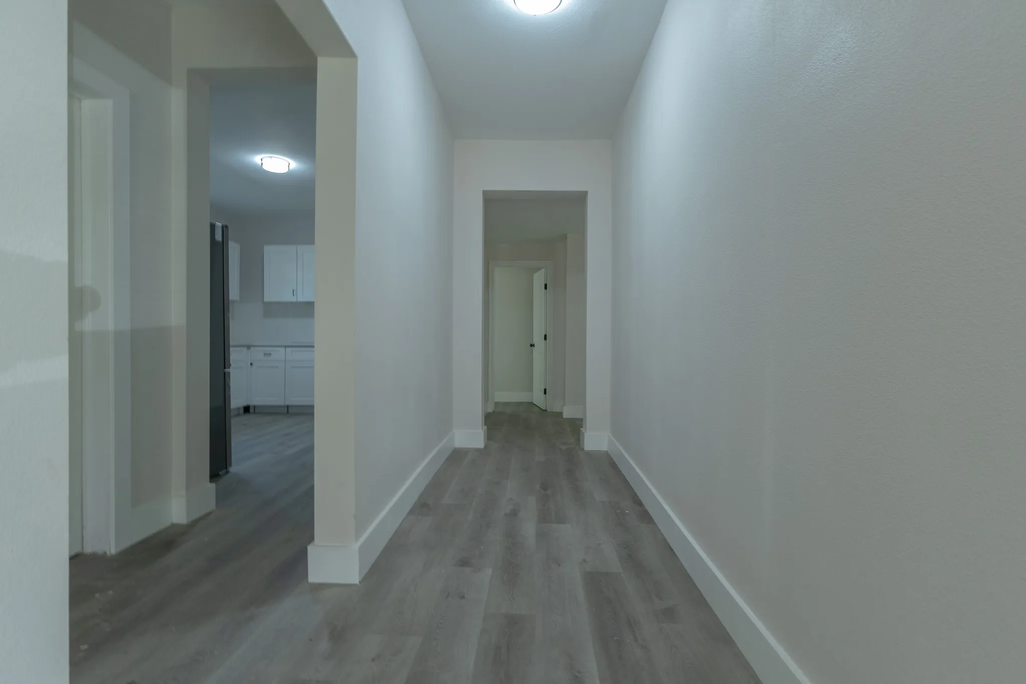Hallway with wood-finish flooring, white baseboards, and neutral wall paint