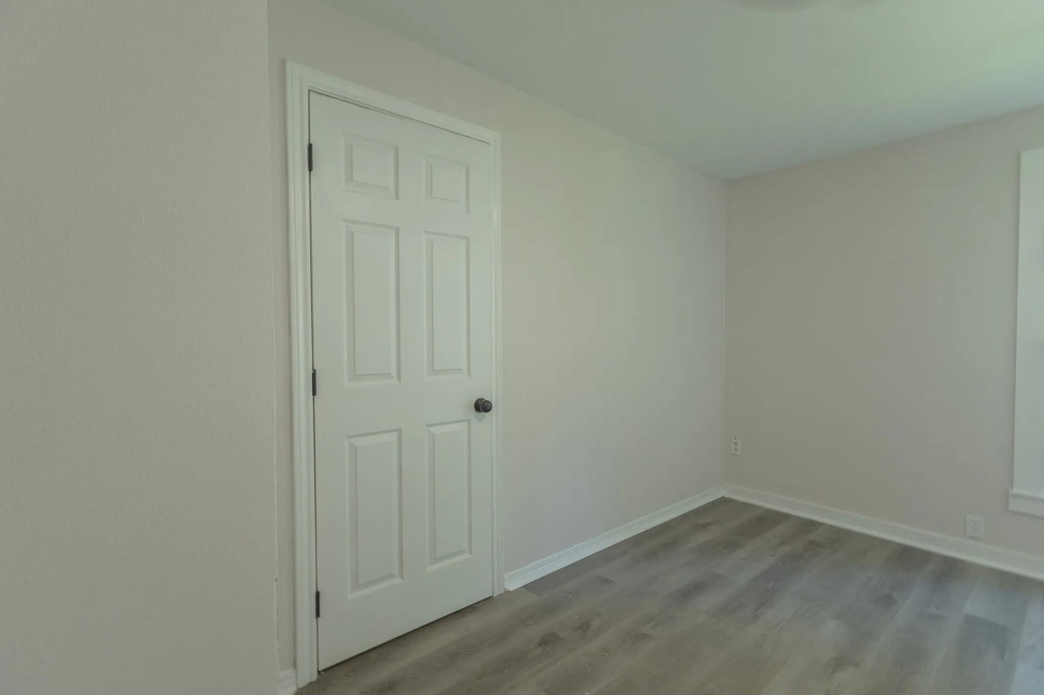 Interior room featuring light-colored walls and wood-finish flooring