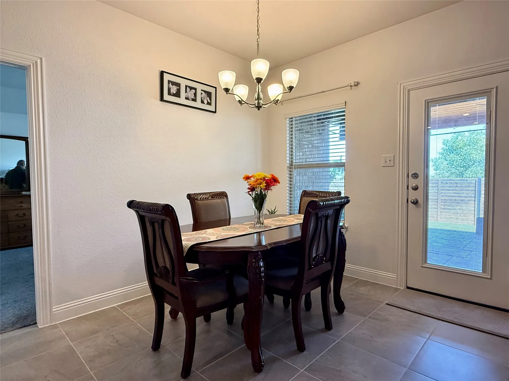 Dining area featuring a five-light chandelier, tile flooring, and a glass-paneled exterior door
