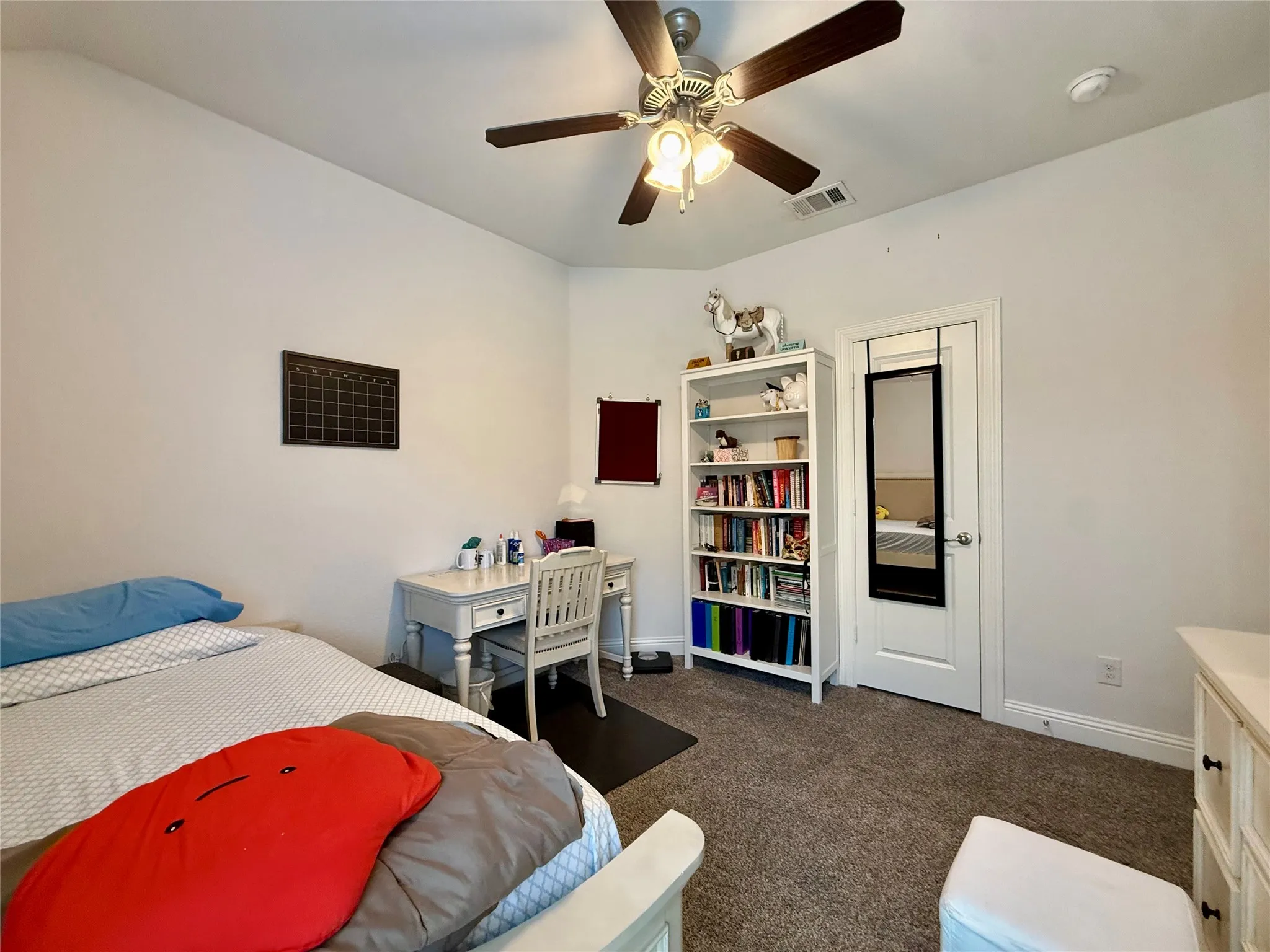 Carpeted room featuring a ceiling fan with integrated lighting, white baseboards, and a white interior door