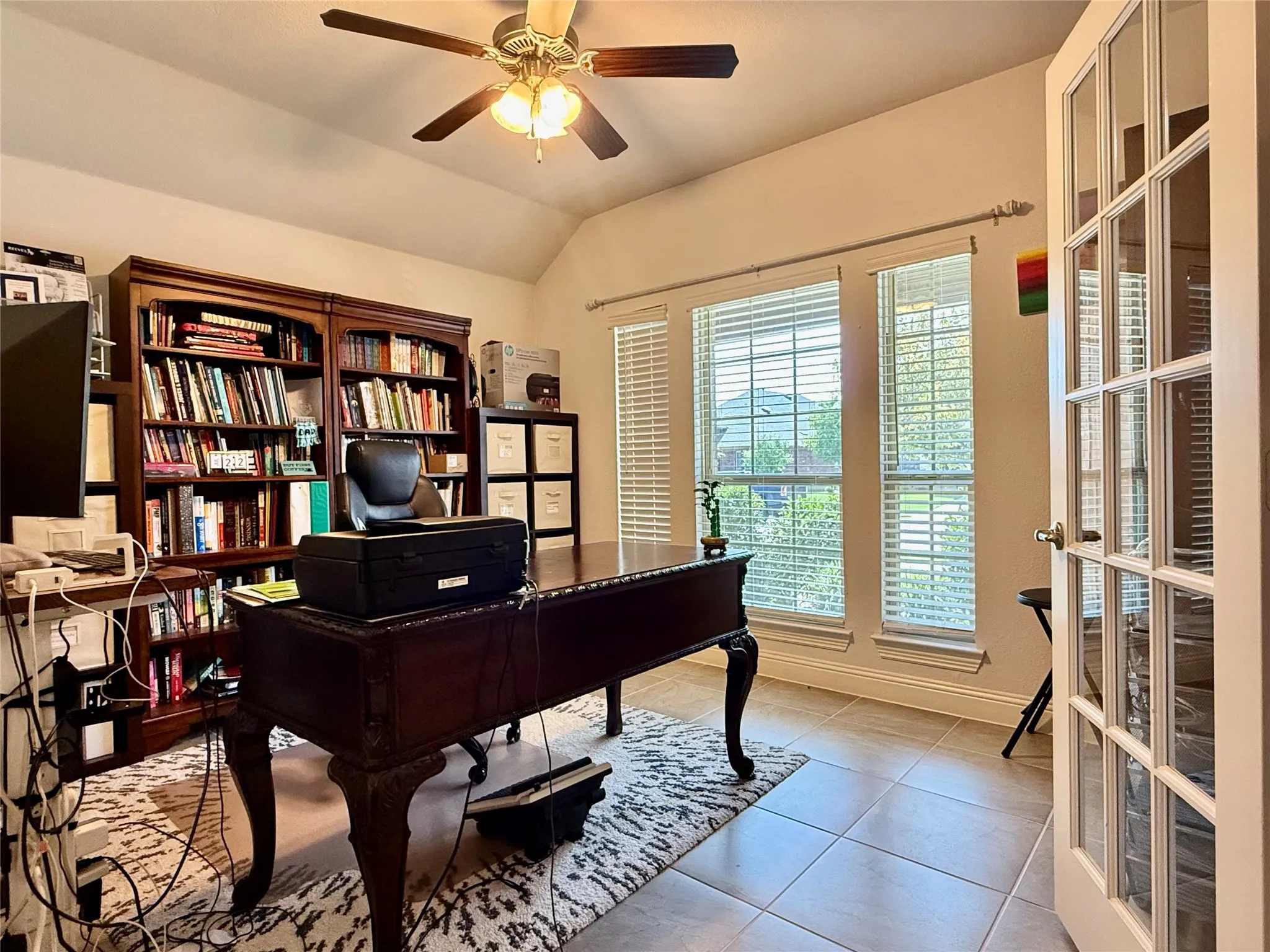 Room featuring French doors with glass panes, two large windows with blinds, a ceiling fan, and tile flooring