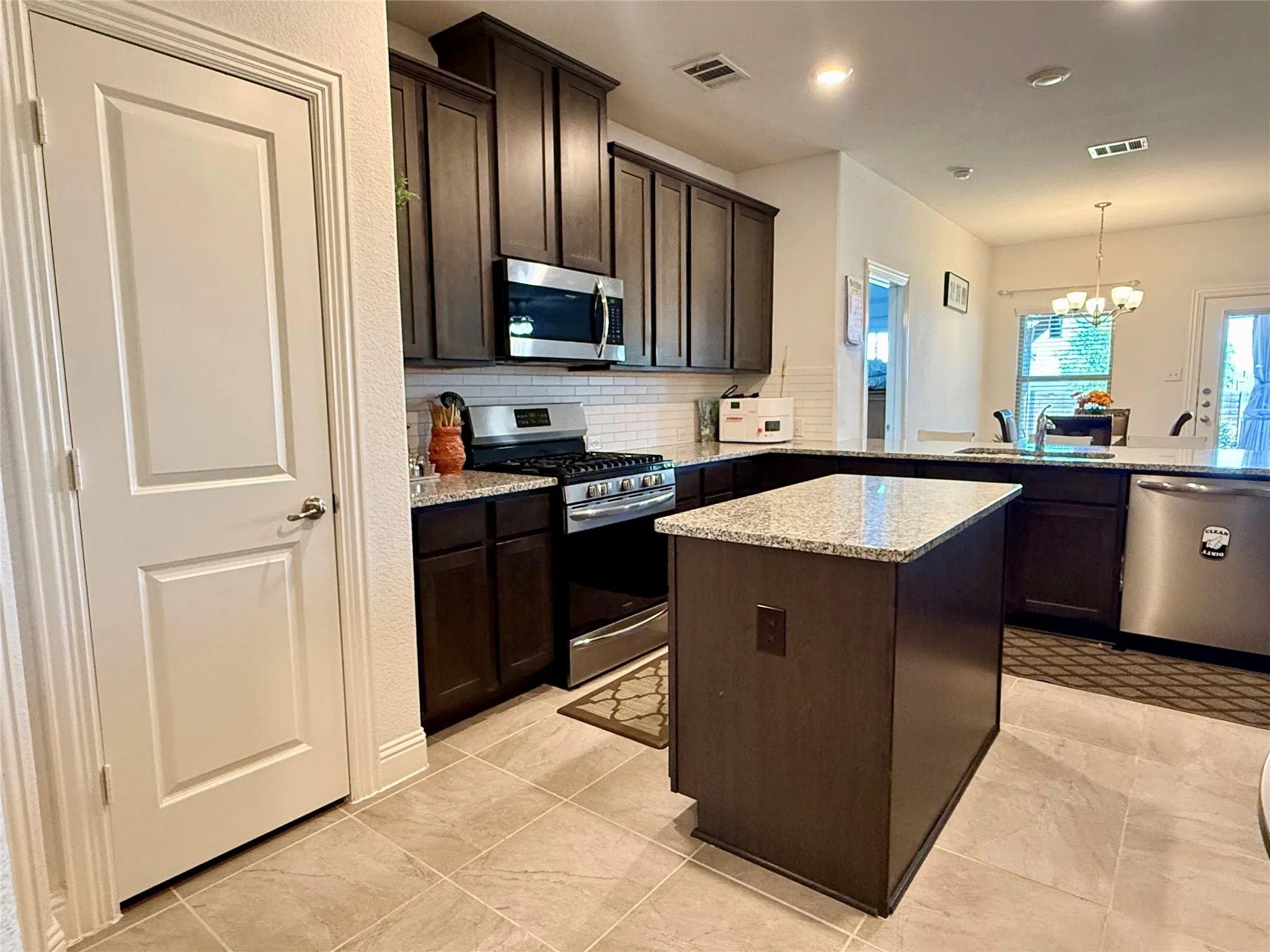 Kitchen featuring dark cabinetry, granite countertops, and a subway tile backsplash