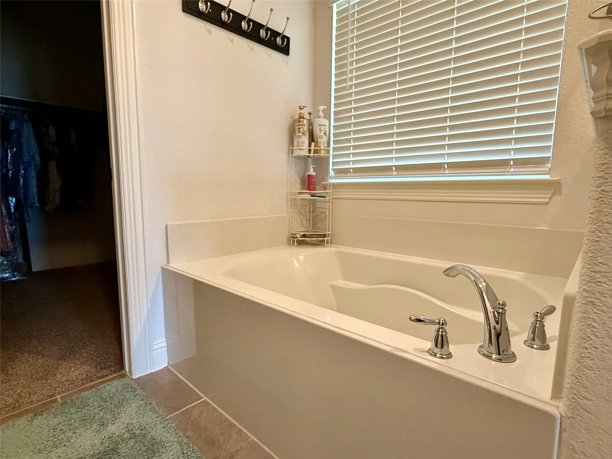 Built-in tub with chrome fixtures and white window blinds