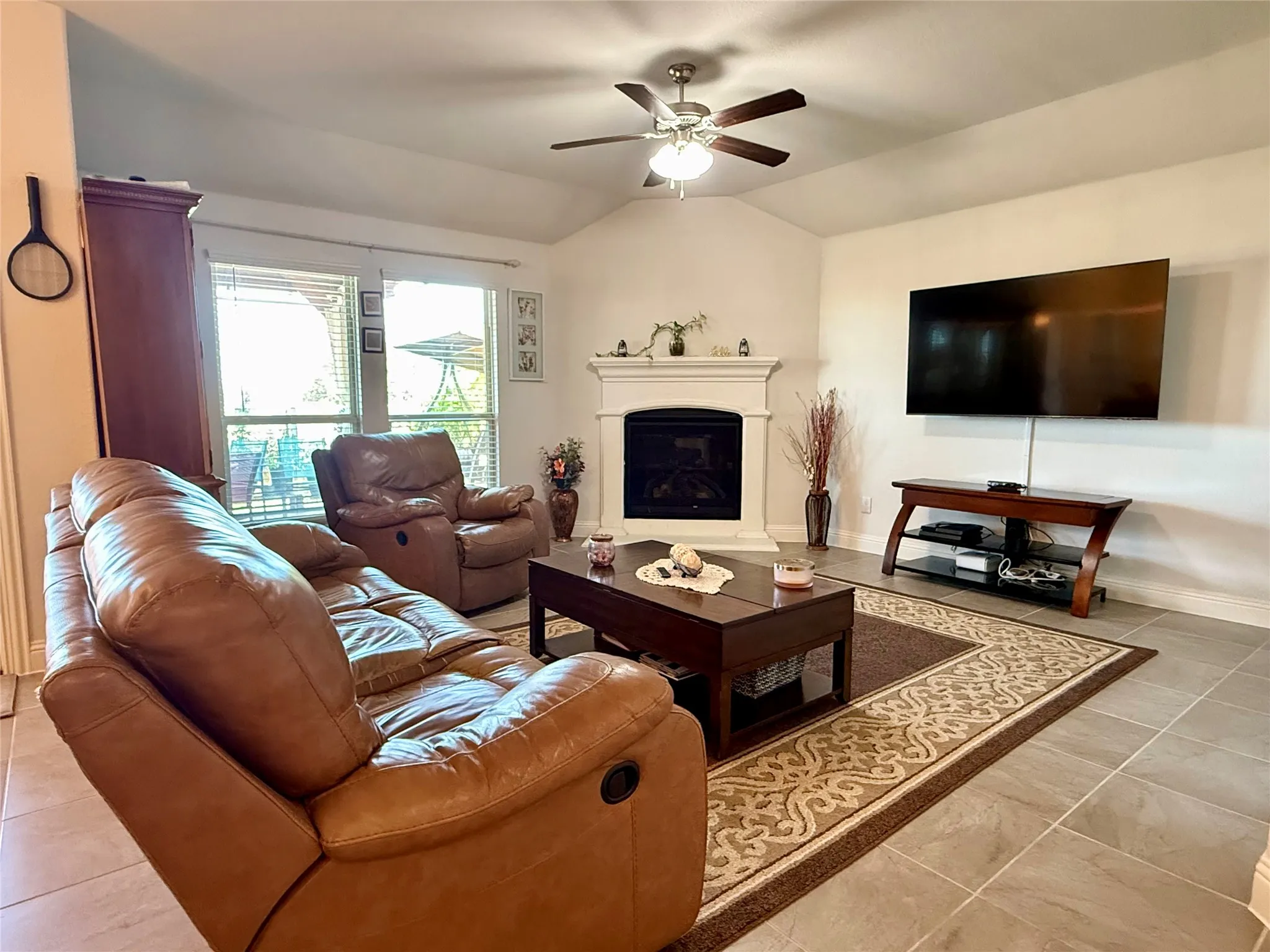 Living area featuring vaulted ceilings, a ceiling fan with integrated lighting, and tile flooring