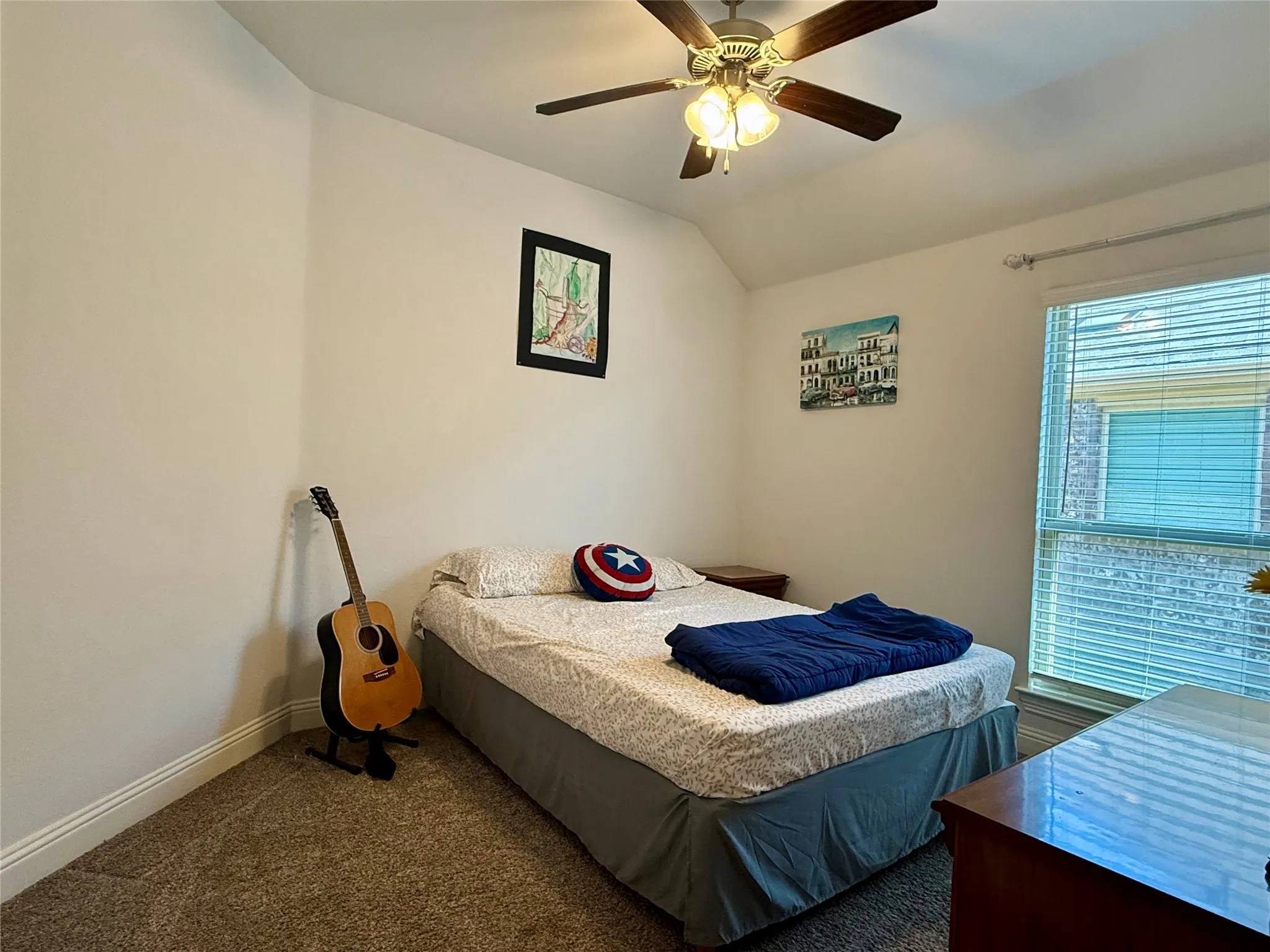 Carpeted room featuring a ceiling fan with light fixture, window with blinds, and white baseboards