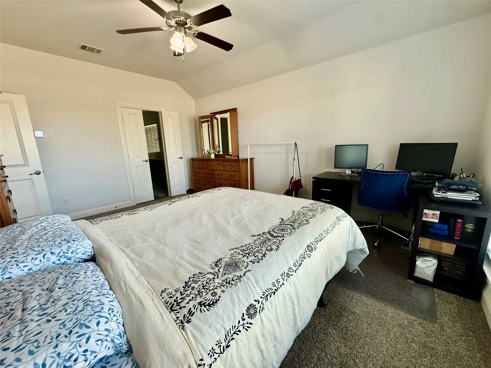 Carpeted room featuring a ceiling fan with light fixture, vaulted ceiling, and white panel doors