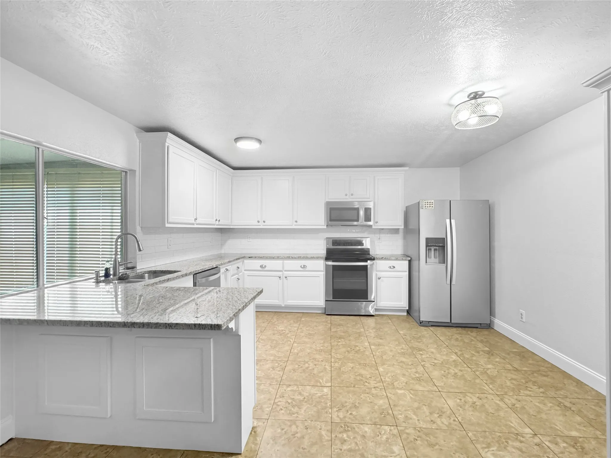Kitchen featuring white cabinetry, granite countertops, stainless steel appliances, and tile​​‌​​​​‌​​‌‌​‌‌​​​‌‌​‌​‌​‌​​​‌​​ flooring