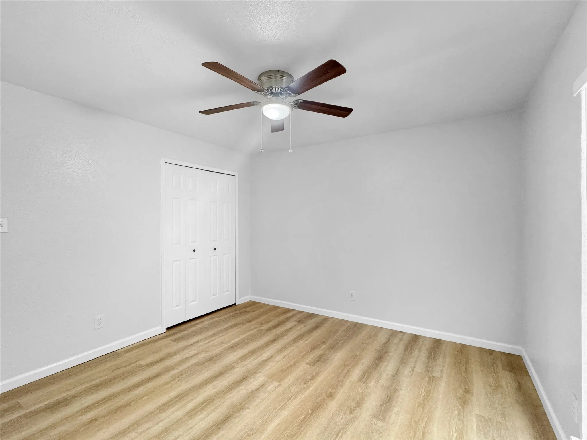 Room featuring wood-finish flooring, white baseboards, and light gray walls