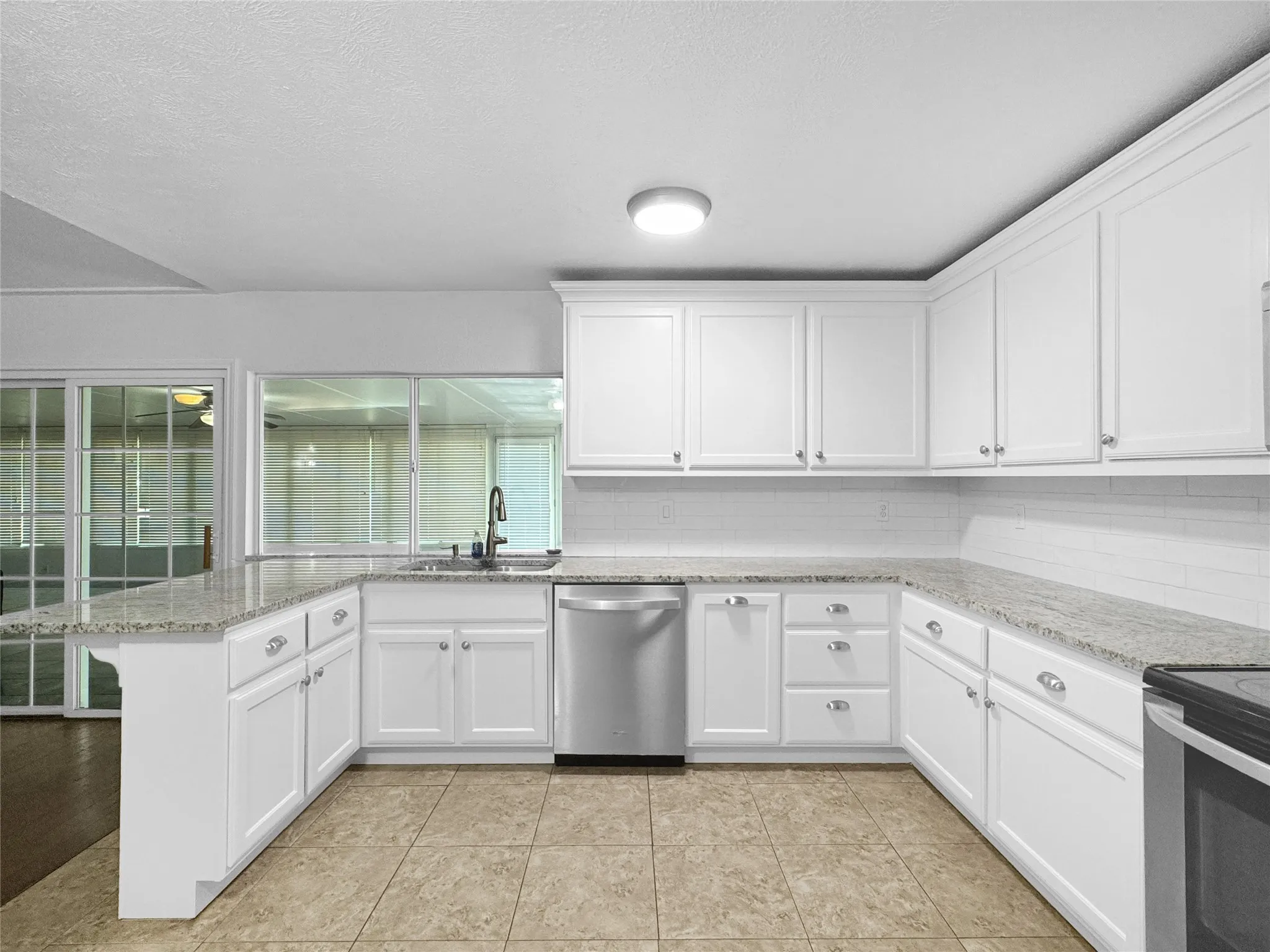 U-shaped kitchen featuring white cabinetry, granite-finish countertops, and a white subway tile backsplash