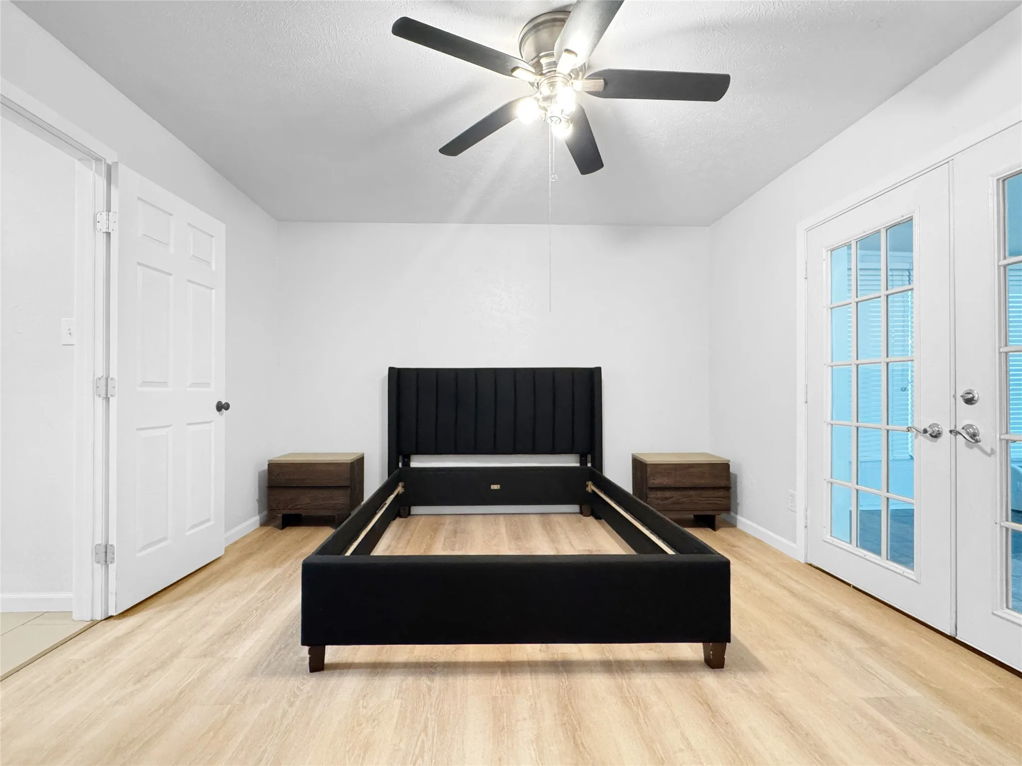 Bright interior space featuring light wood-finish flooring, a ceiling fan with integrated lighting, and white walls