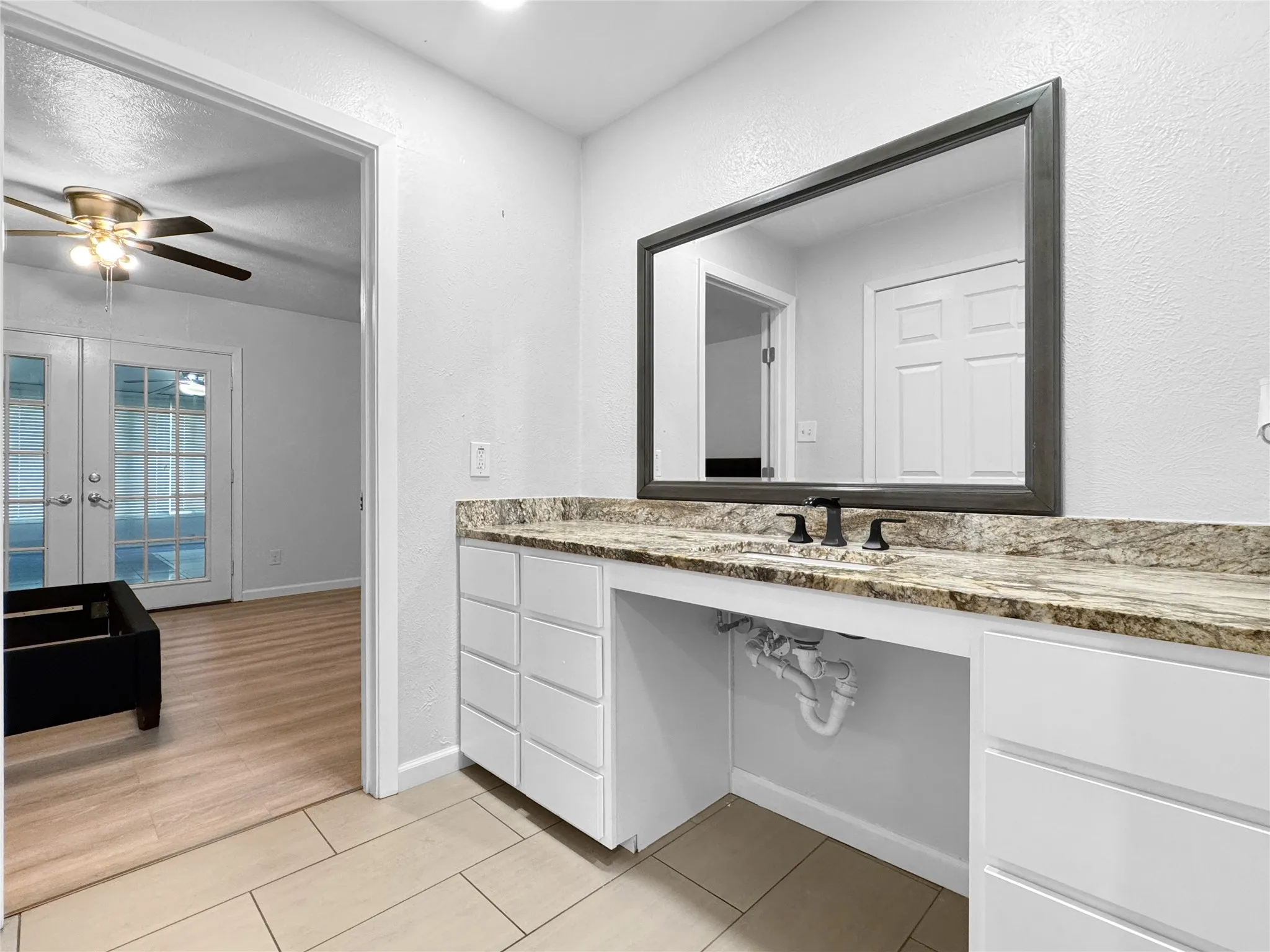 Vanity area featuring a built-in countertop with an undermount sink, a matte black faucet, and a framed wall mirror