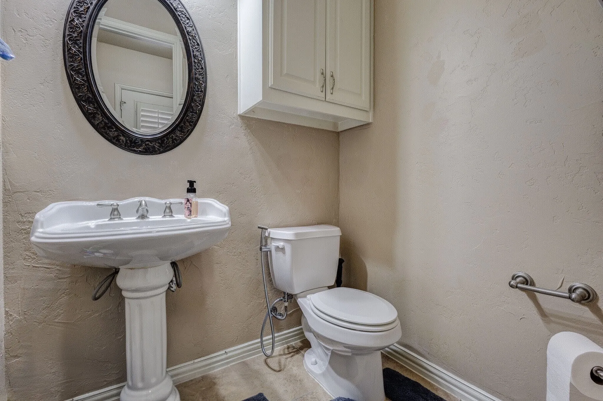 Pedestal sink with an ornate black framed mirror