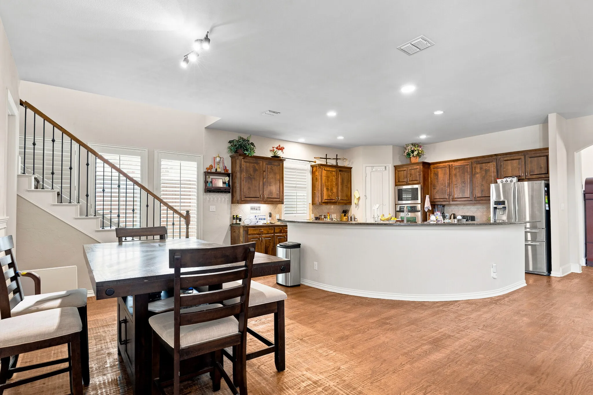 Open-concept living space featuring wood-finish flooring and a staircase with wrought iron balusters