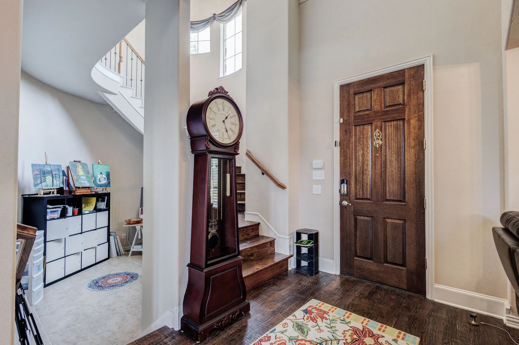 Entryway featuring dark wood-finish flooring, a paneled wood entry door, and a curved staircase with wood treads and a white balustrade