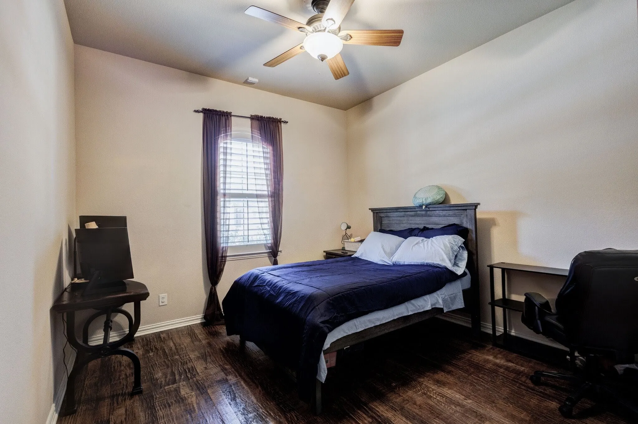 Bedroom featuring wood-finish flooring, a window with blinds, a ceiling fan with light fixture, and neutral wall tones