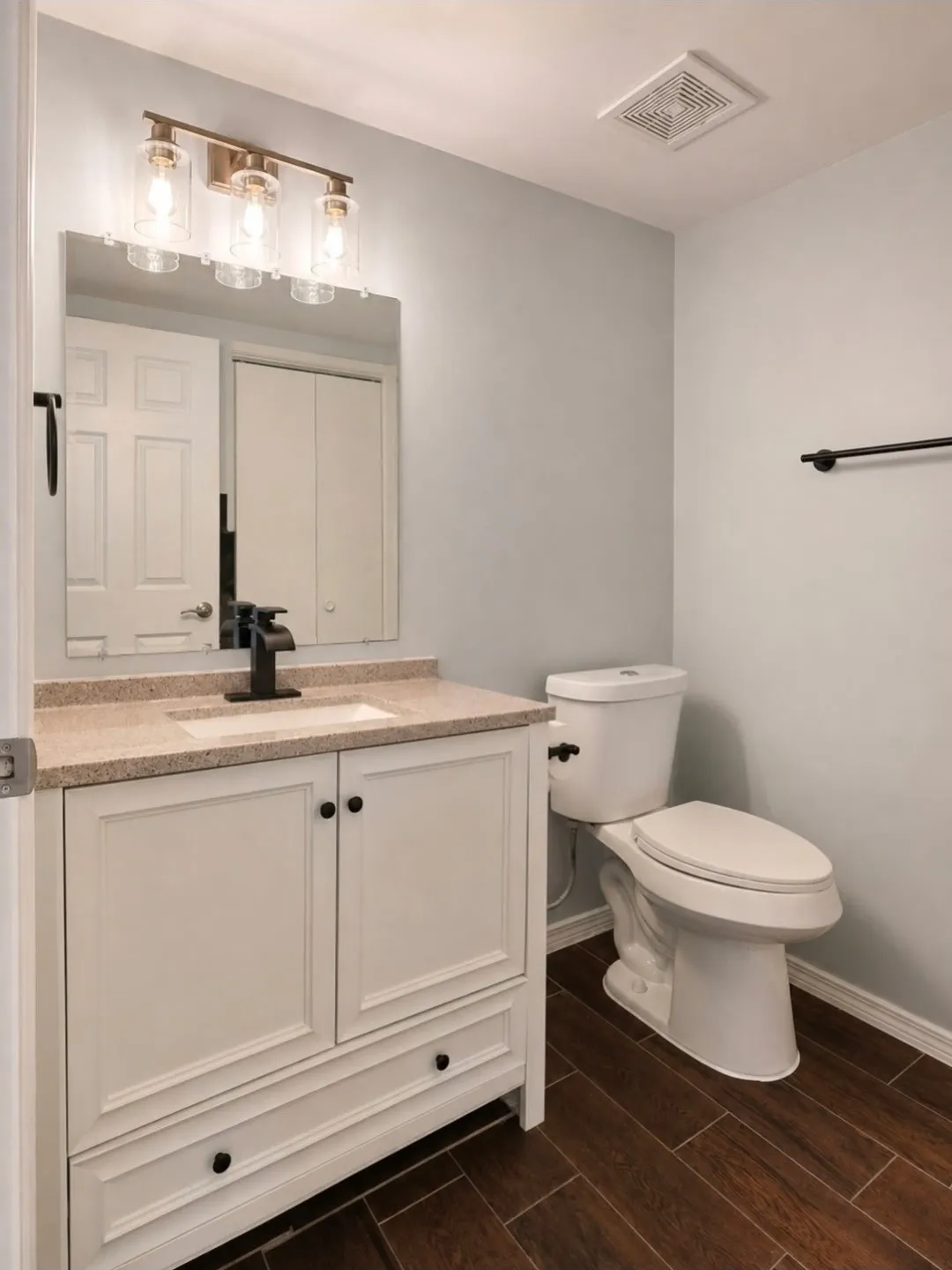 Bathroom featuring a white vanity with a stone-finish countertop, undermount sink, and a black faucet