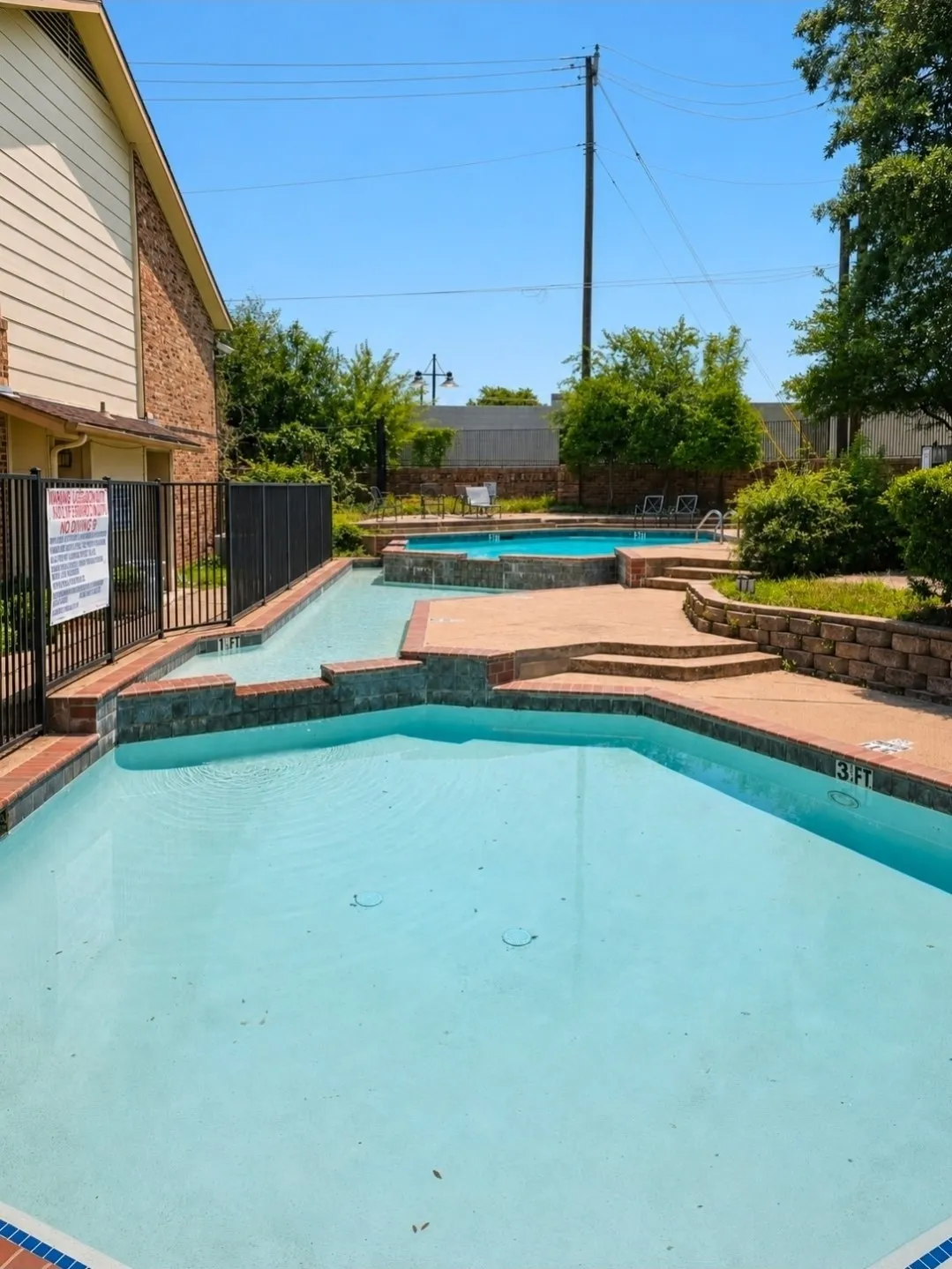 Multi-level swimming pool area featuring a blue-tiled wading section and an elevated spa