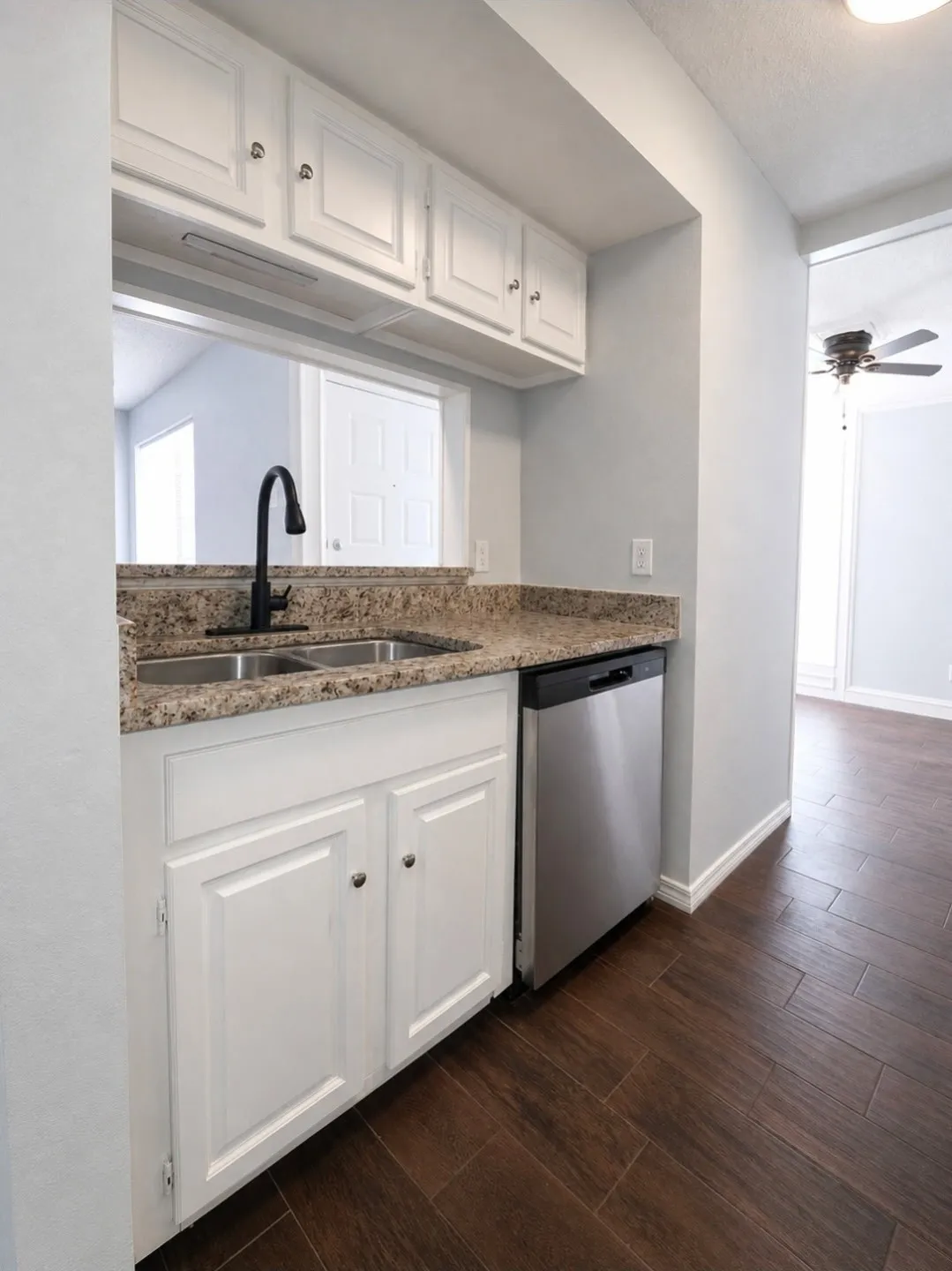 Kitchen featuring white shaker-style cabinetry, granite-finish countertops, and a dual basin stainless steel sink with a matte black faucet