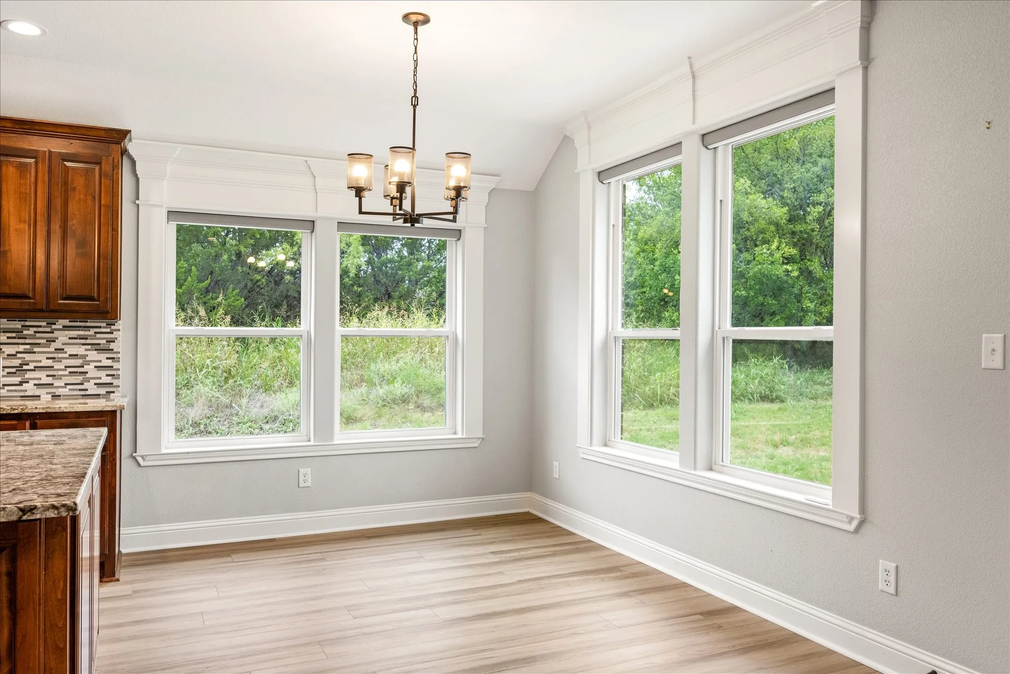 Dining area featuring wood-finish flooring, a contemporary chandelier, and large windows with extensive trim work