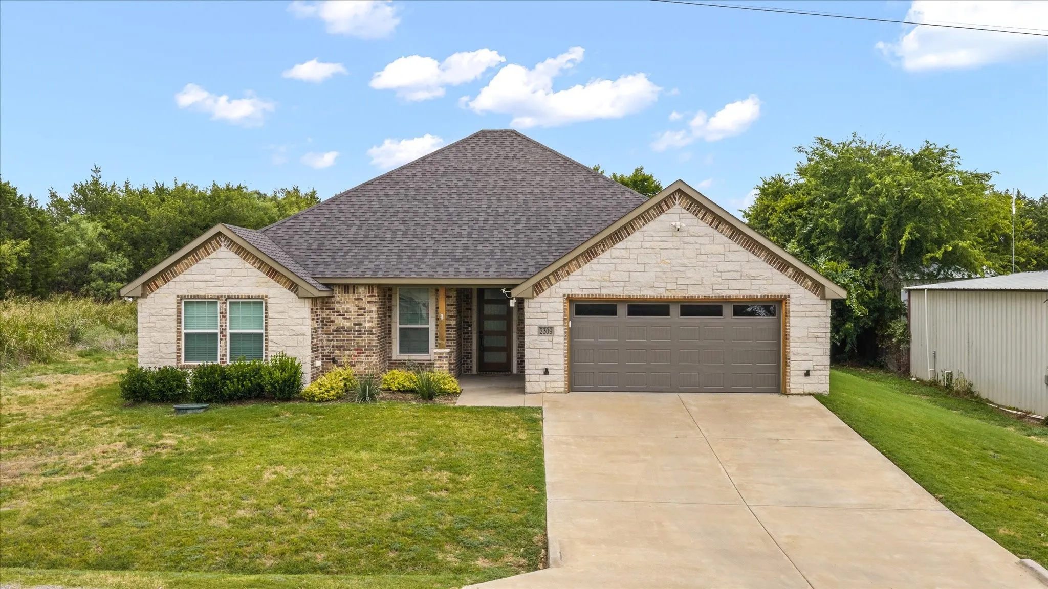 Contemporary ranch-style home featuring a two-car garage, concrete driveway, and a combination of brick and stone masonry on the facade