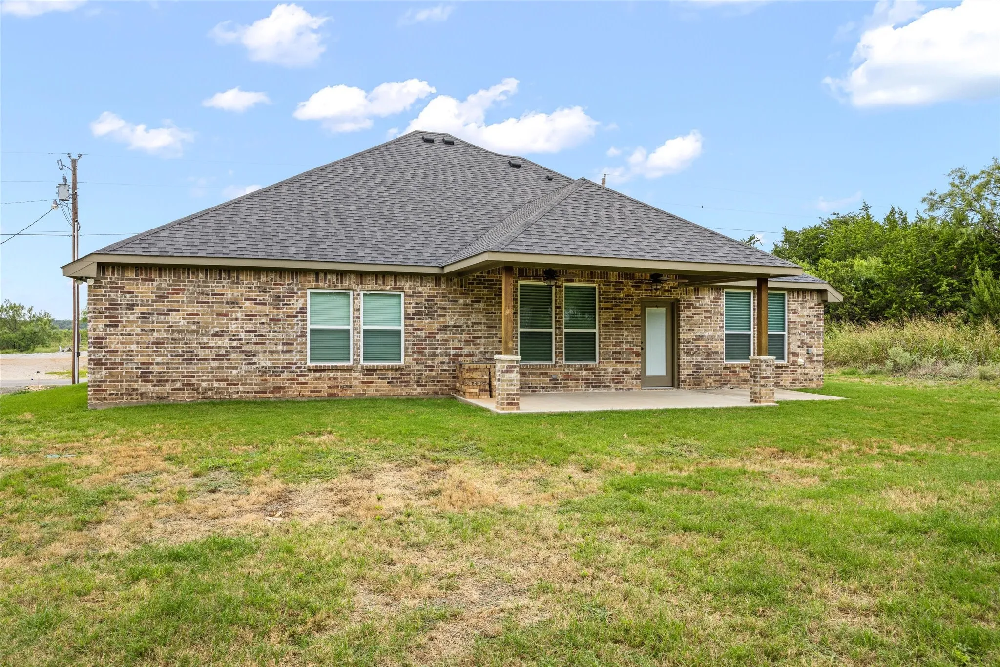 Rear exterior featuring a covered patio with brick columns and wood-finish posts