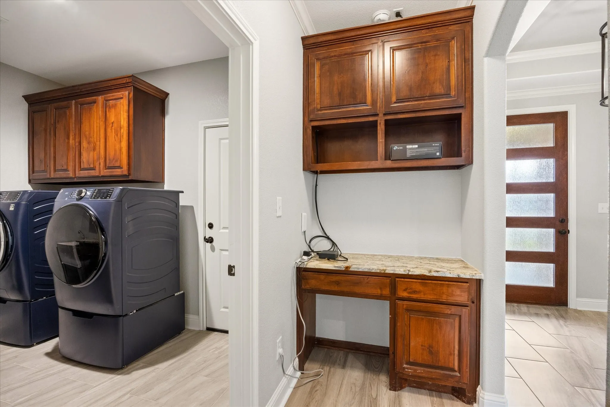 Built-in wood-finish desk with a stone countertop and upper cabinetry