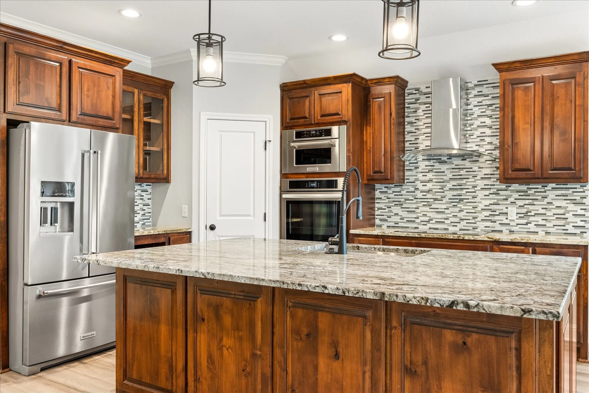 Kitchen featuring a large island with a stone countertop, rich wood cabinetry, stainless steel appliances, a mosaic tile backsplash, and recessed lighting
