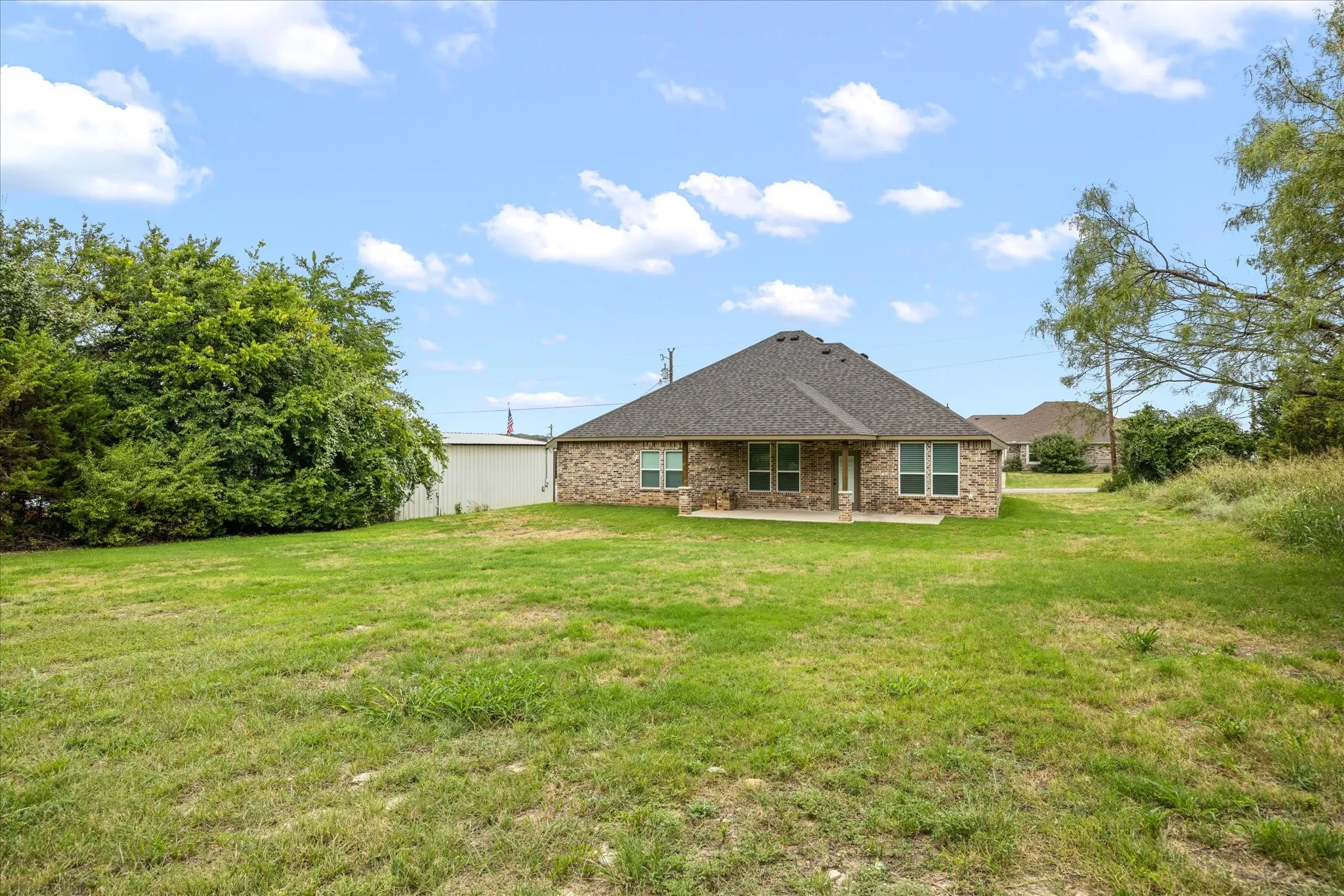 Spacious backyard featuring an expansive lawn and mature trees