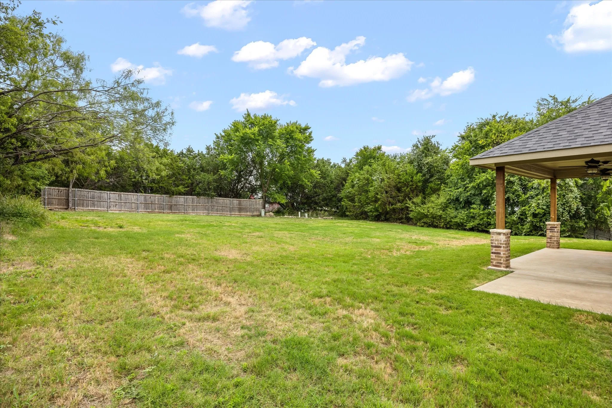 Expansive backyard featuring a manicured lawn and mature trees