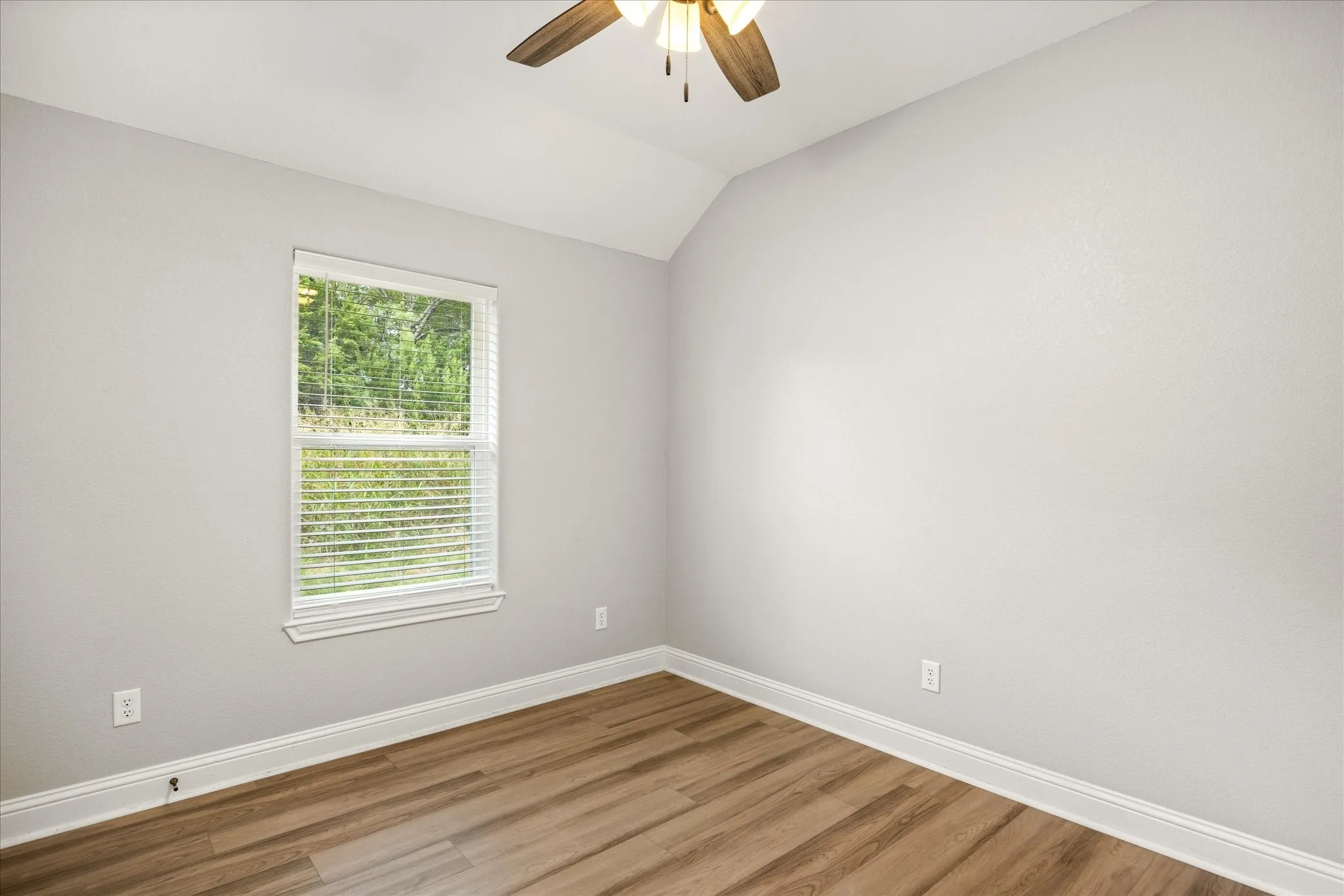 Room with wood-finish flooring, a white trim package, and a window with blinds