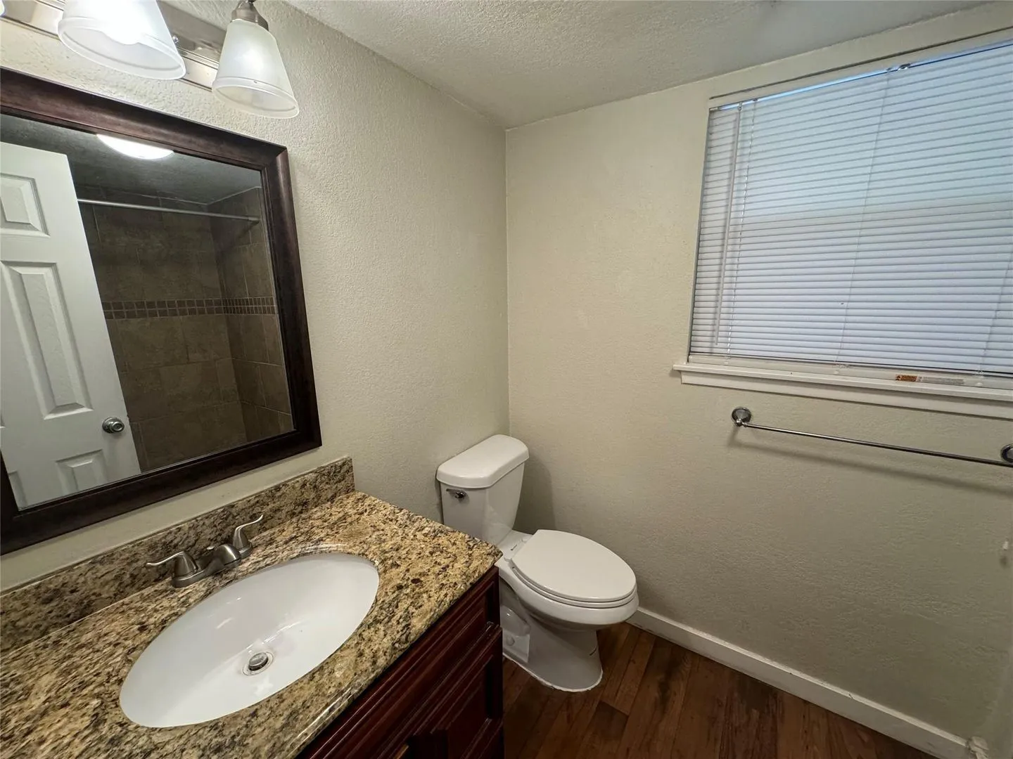 Bathroom featuring a vanity with a granite-style countertop, an undermount oval sink, and a framed mirror