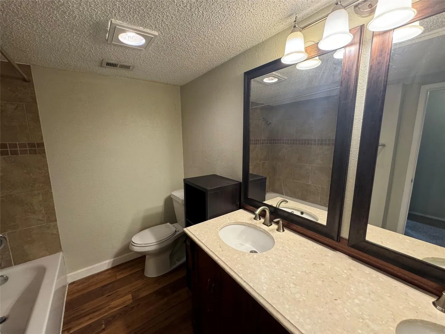 Bathroom featuring a double vanity with light-toned countertops, dark wood-finish cabinetry, and framed mirrors