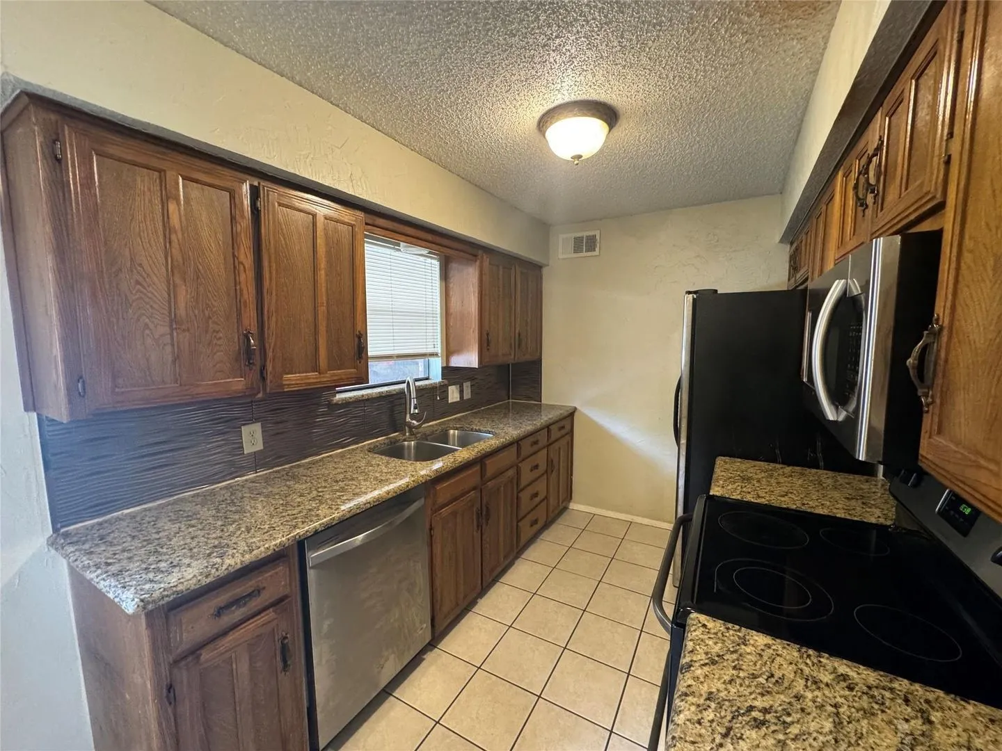 Kitchen featuring wood cabinetry, granite-finish countertops, and a tile backsplash