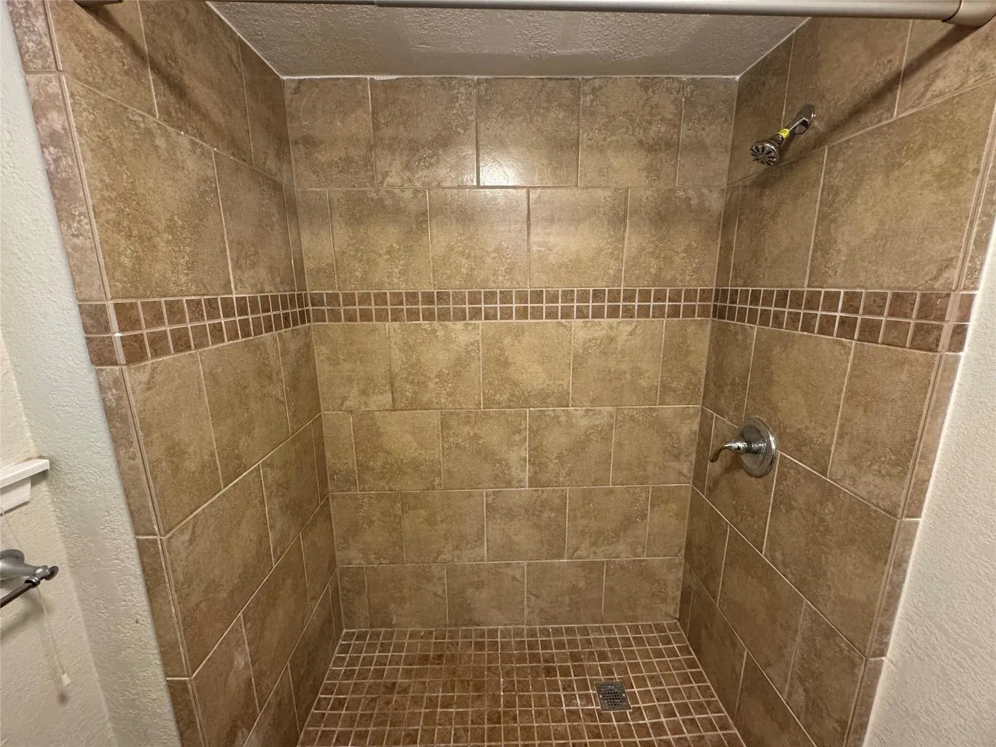 Tiled shower with a decorative mosaic band and chrome fixtures