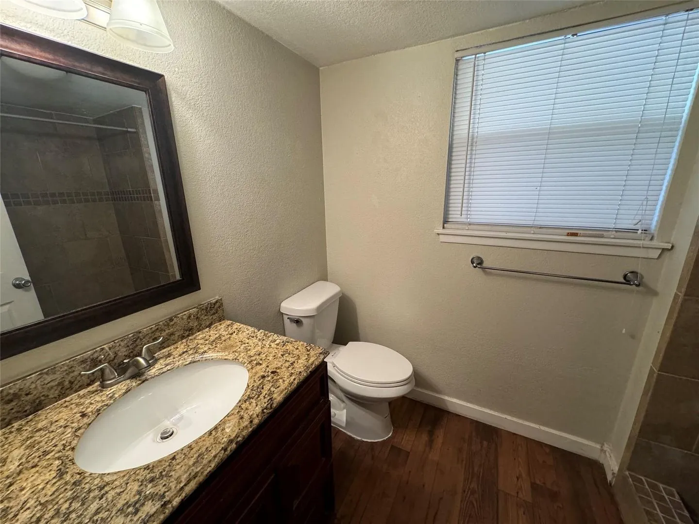 Bathroom featuring a vanity with a granite-look countertop, an undermount sink, and wood-finish flooring
