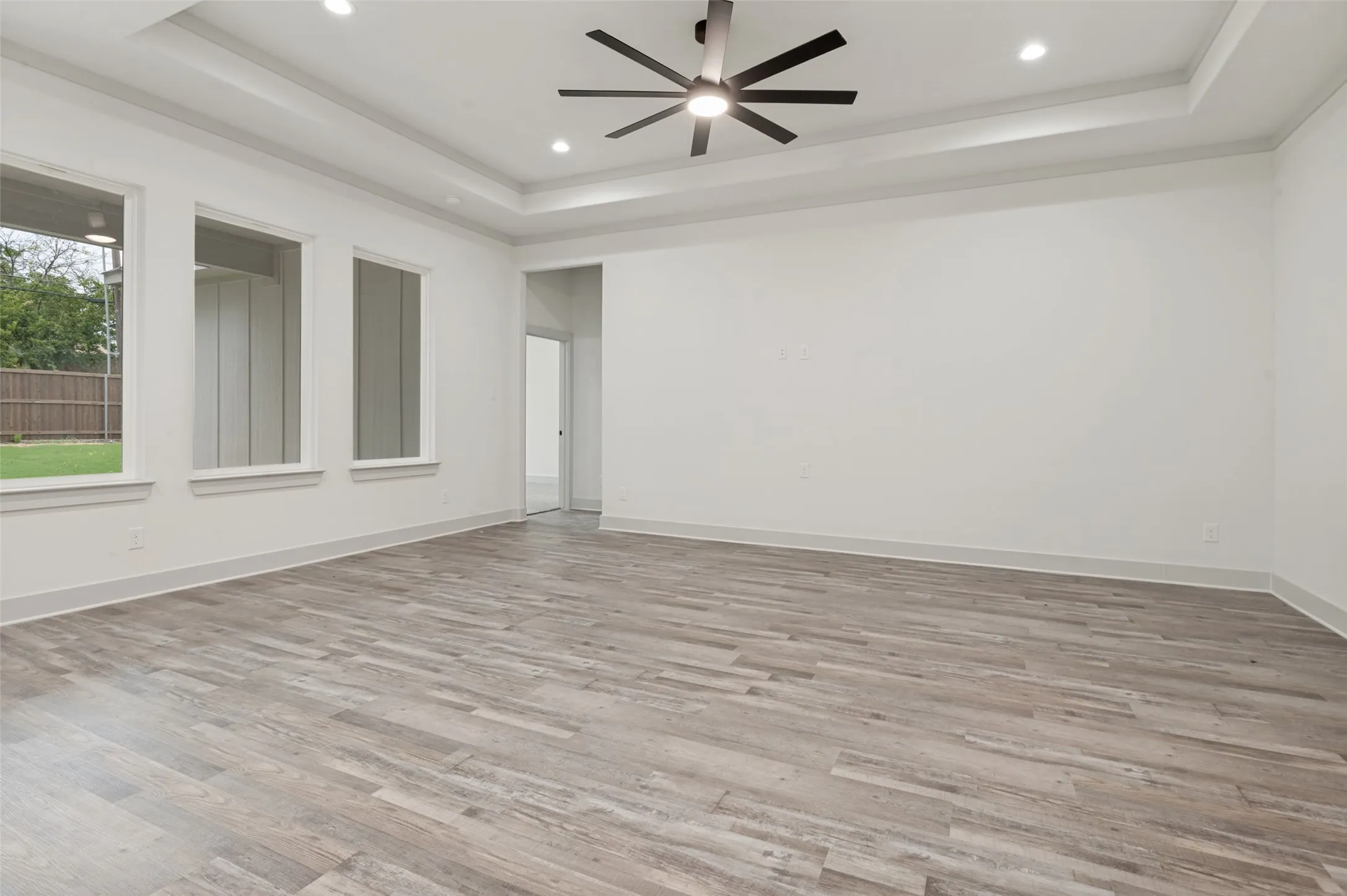 Spacious room with wood-finish flooring, recessed lighting, and a contemporary ceiling fan