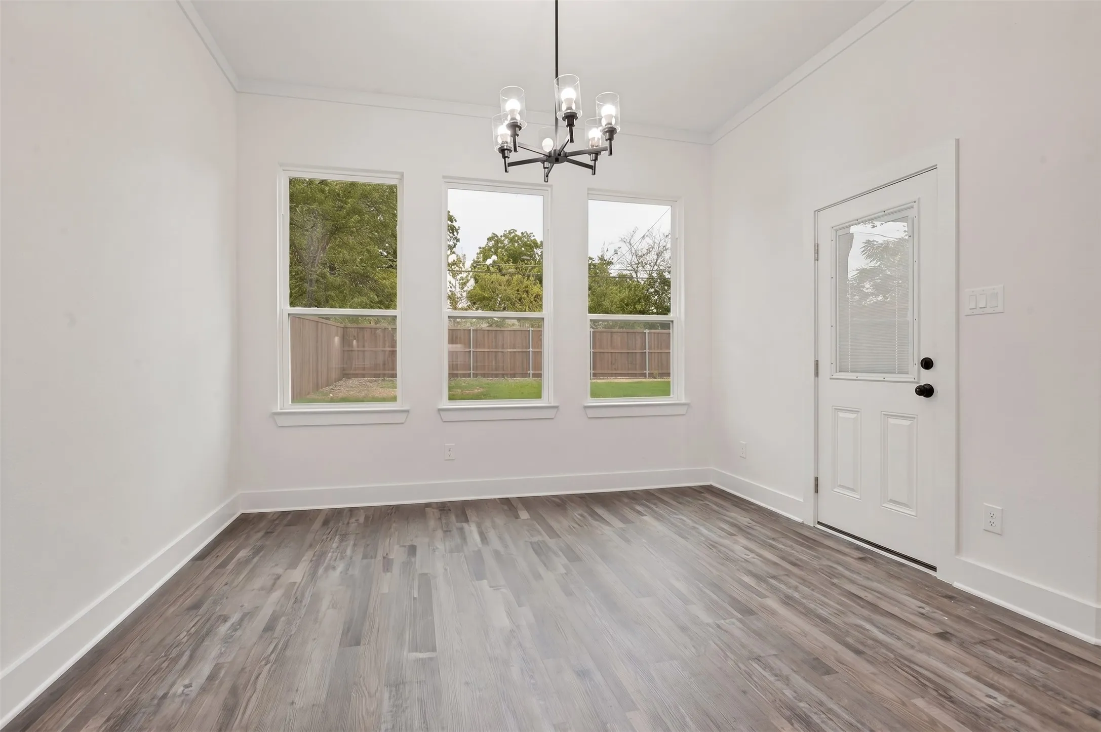Wood-finish flooring, white walls, and a contemporary chandelier