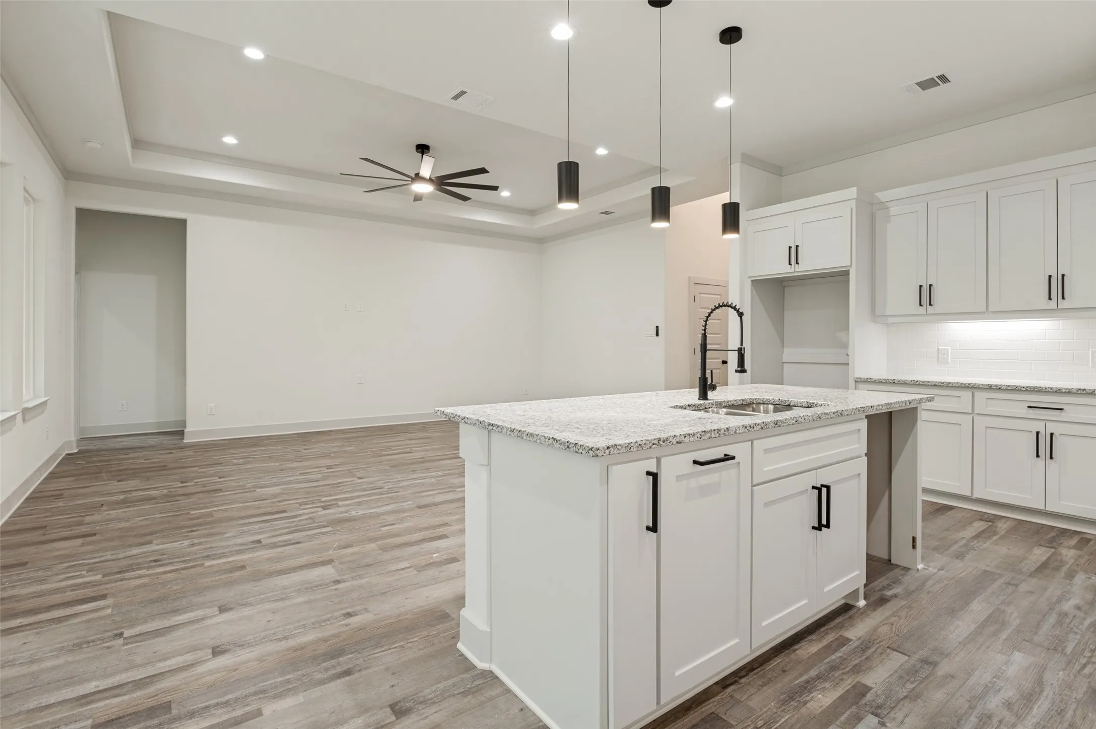 Modern kitchen featuring a large white cabinetry island with waterfall countertop, stainless steel appliances, and pendant lighting