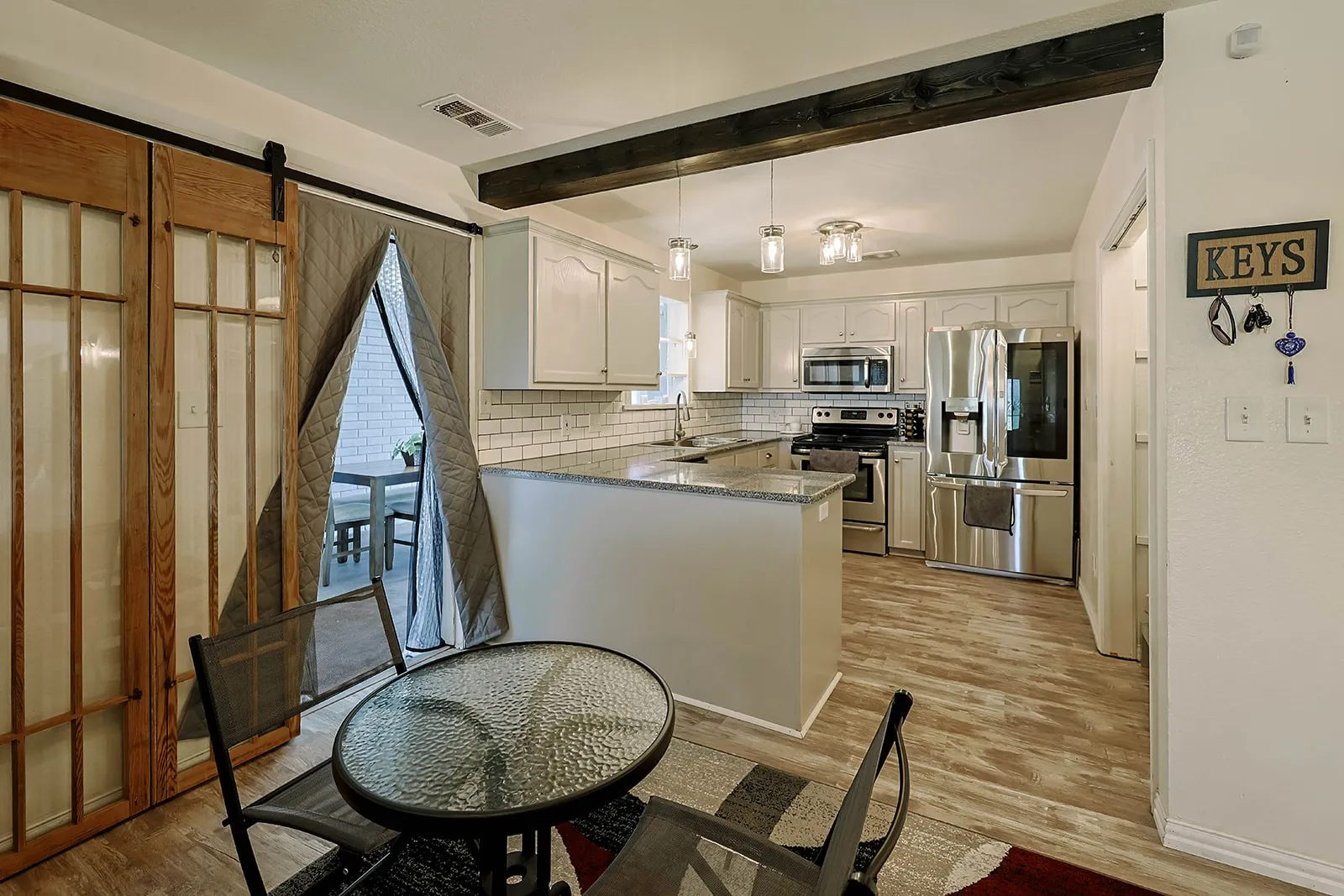 Kitchen with light wood-finish flooring, white cabinetry, and stainless steel appliances