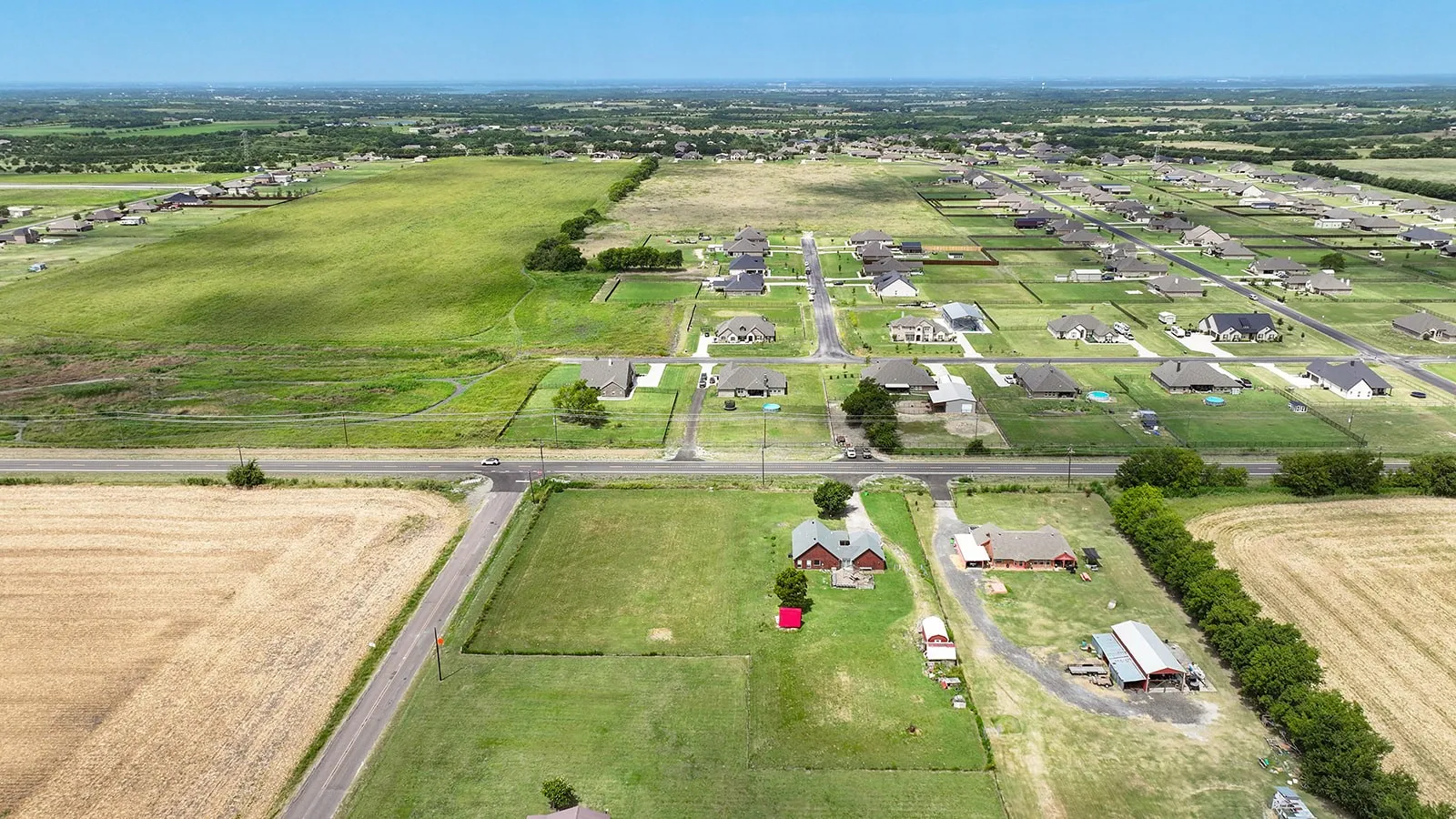 Expansive land parcel featuring open fields and established residential areas nearby