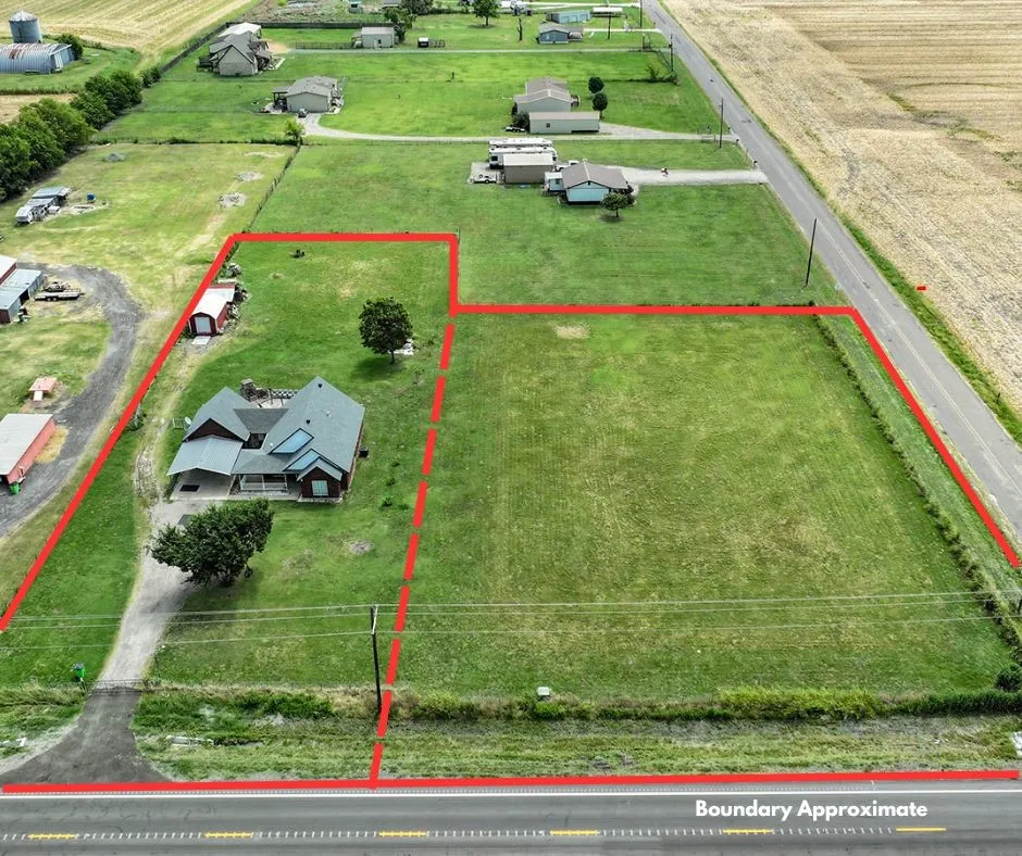 Expansive residential lot featuring a ranch-style home with a metal roof, situated on approximately 5+ acres of manicured lawn with mature trees