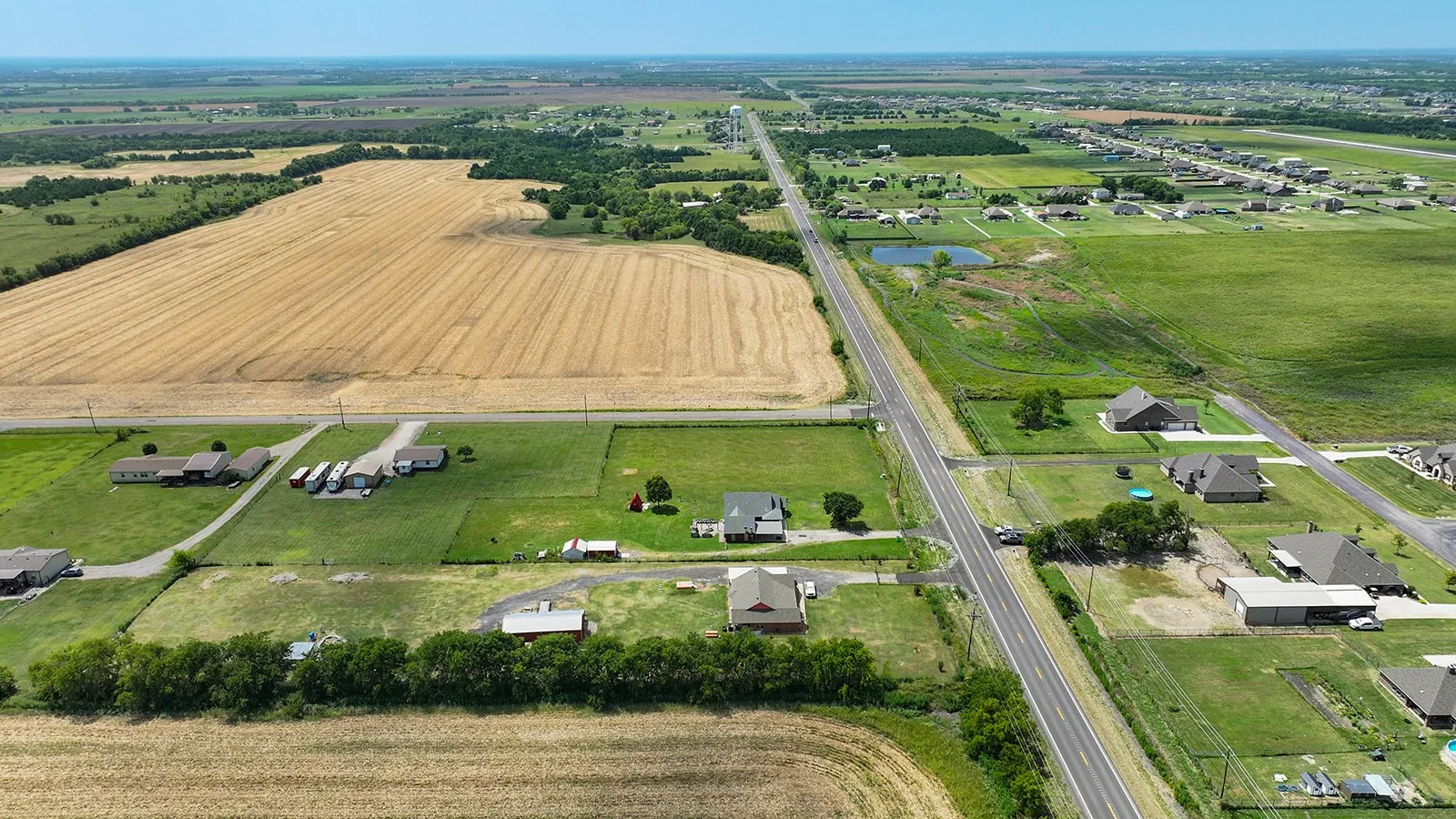 Aerial perspective showcasing a rural landscape with open fields and scattered residential properties