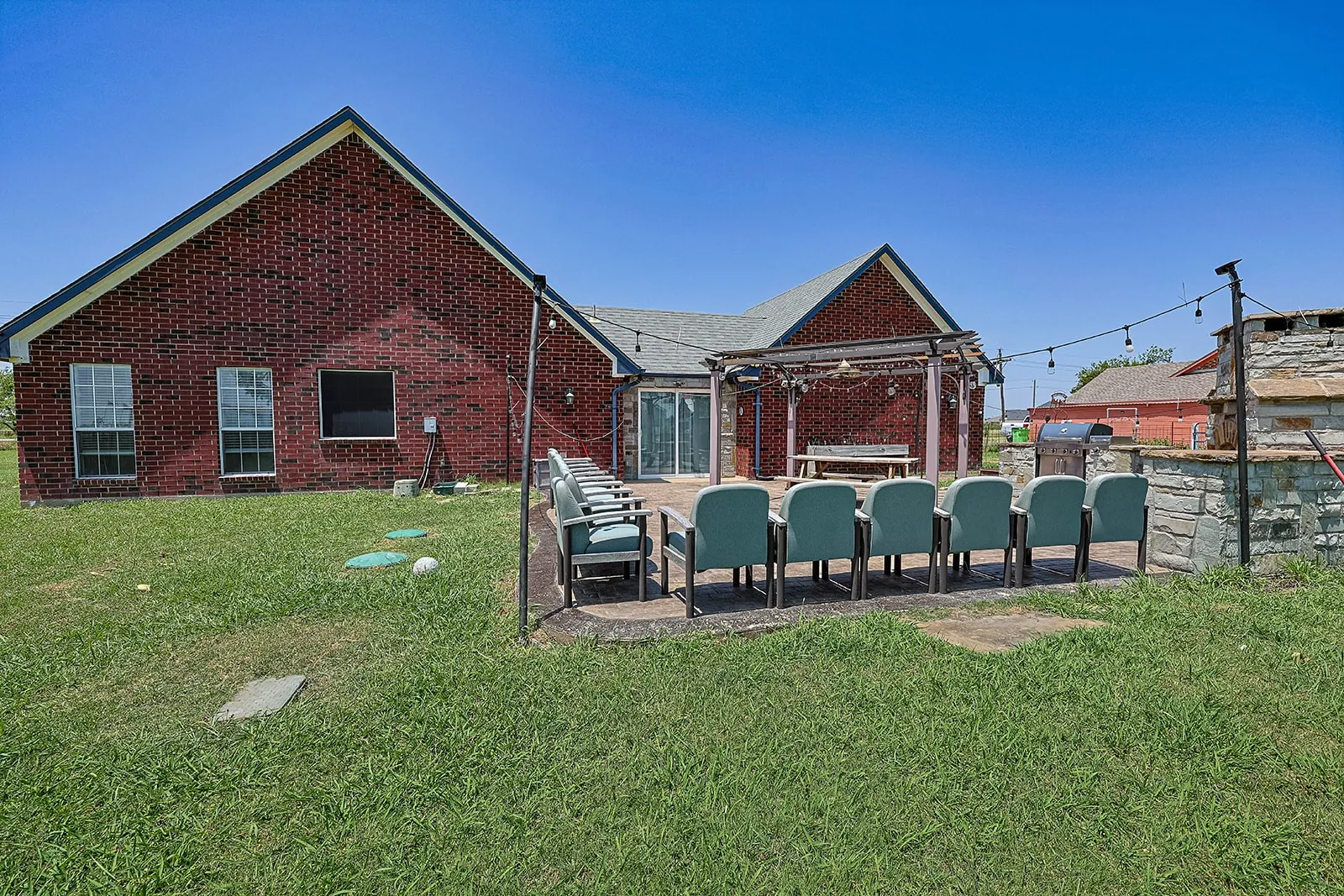 Expansive outdoor patio area featuring a wooden pergola and a built-in stone outdoor fireplace