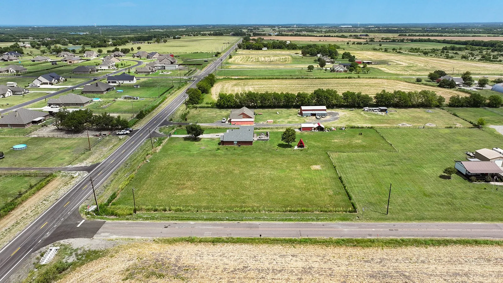 Expansive rural landscape featuring a main thoroughfare, agricultural fields, and scattered residential properties
