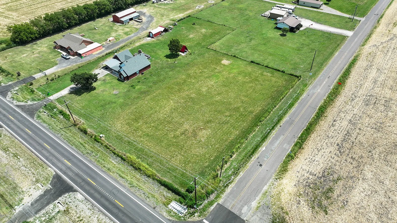 Expansive land parcel featuring multiple structures, including a primary residence with a dark green roof and a secondary red-roofed building